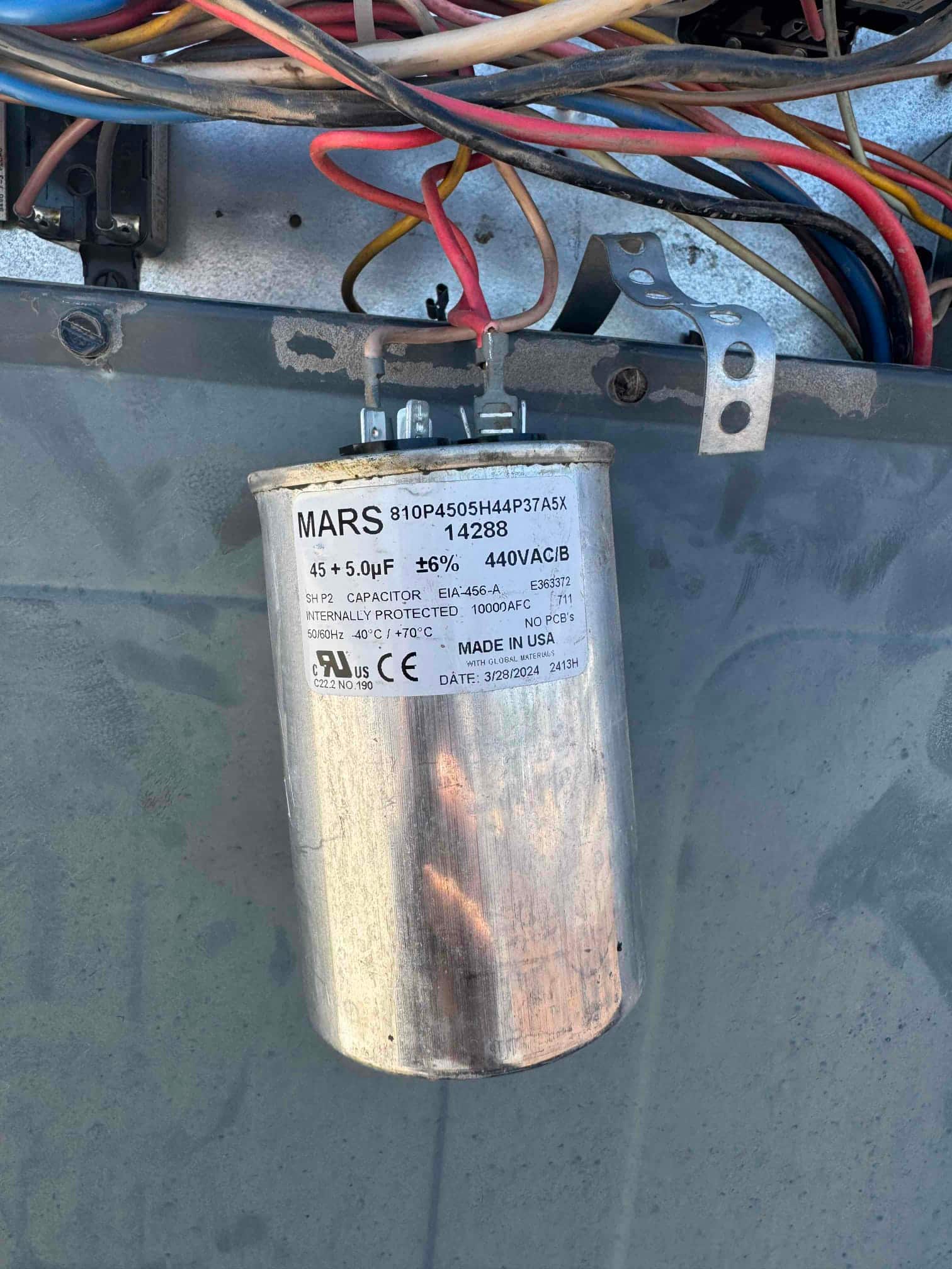 Dual-run capacitor mounted in the condenser, labeled 45 + 5 μF ±6% 440 VAC, with connected wires and clean terminals.