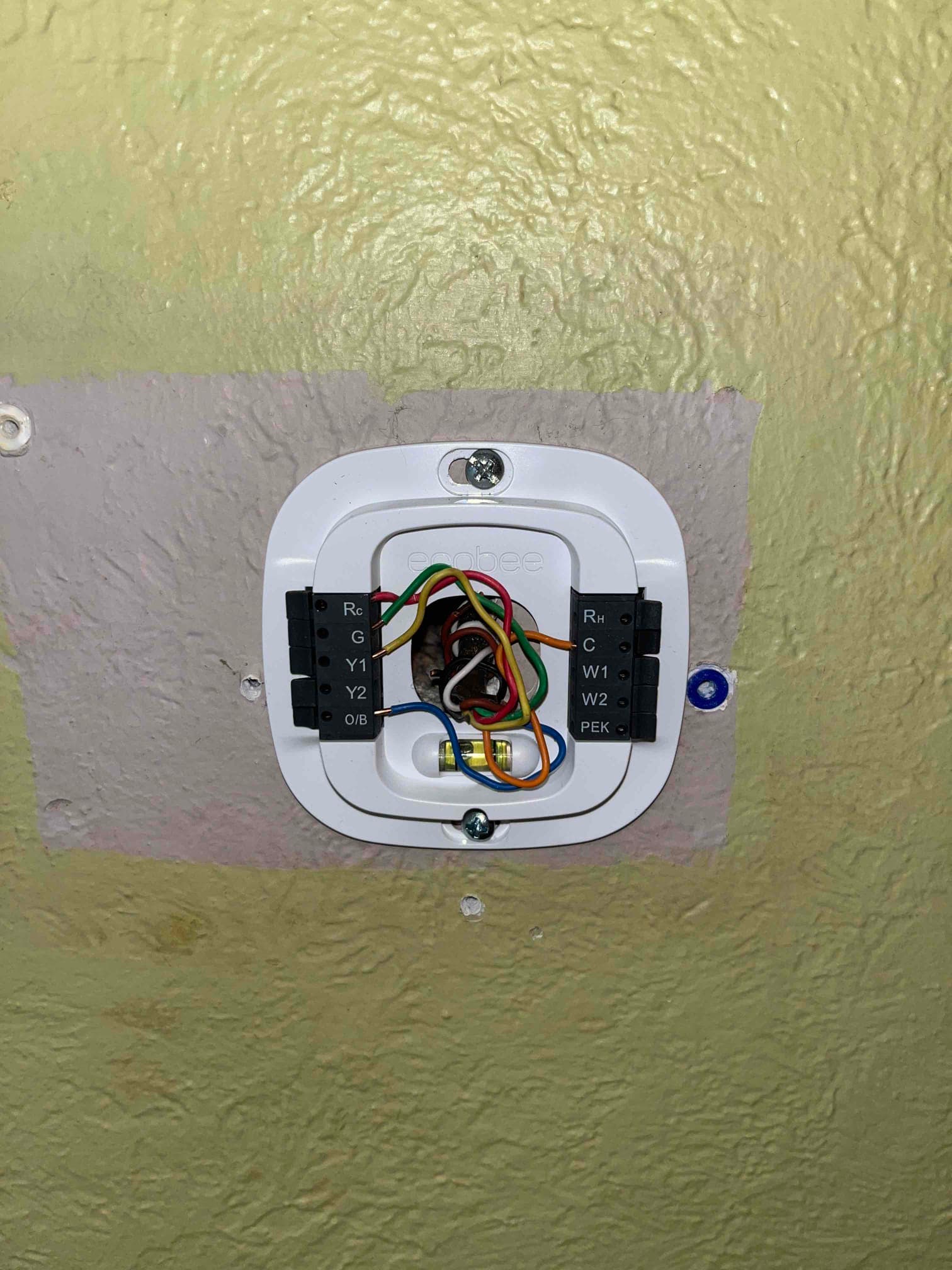 Ecobee smart thermostat base mounted on wall with control wires connected to Rc, G, Y1, W1, and C terminals.