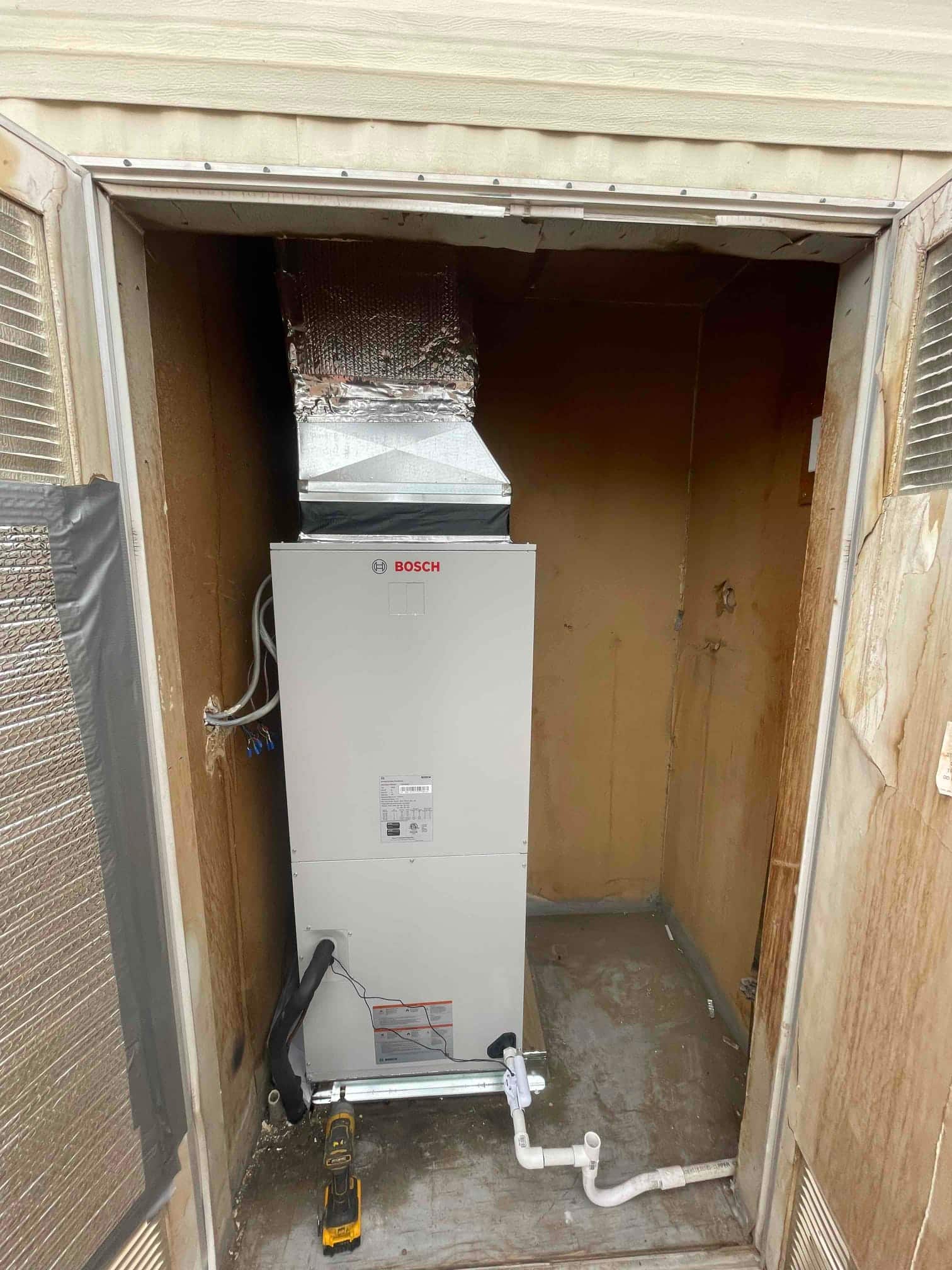 New air handler installed in closet with insulated supply plenum and newly plumbed PVC condensate drain with cleanout.