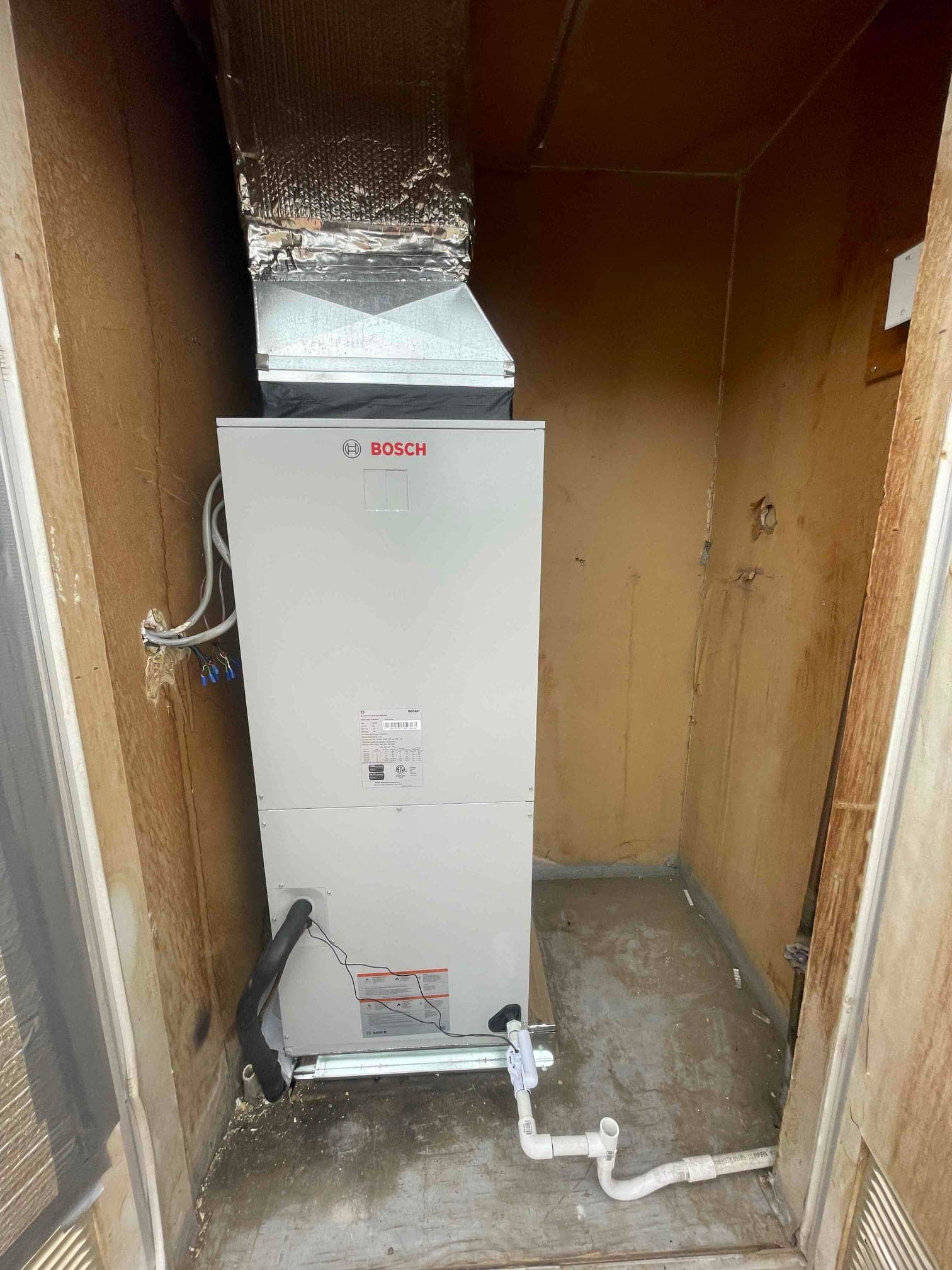 New air handler installed with insulated supply plenum, condensate drain with cleanout, and sealed line set penetration.