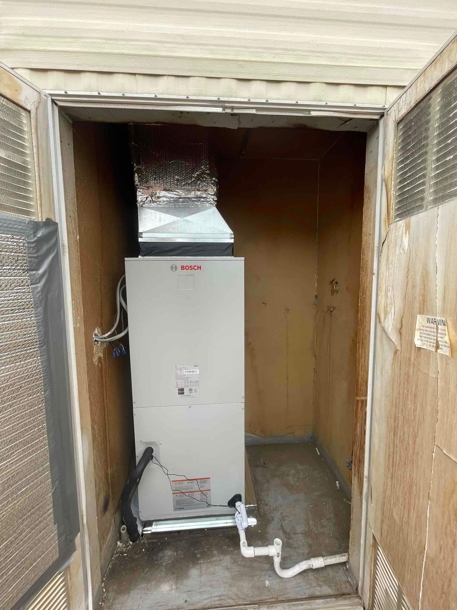 New air handler installed with lined supply plenum, insulated refrigerant line, electrical whip, and condensate drain with cleanout and trap.