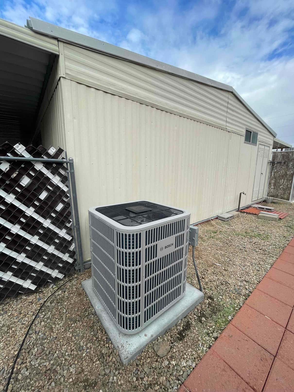 New outdoor condenser set on a level pad with electrical disconnect mounted nearby and line set routed along the wall.