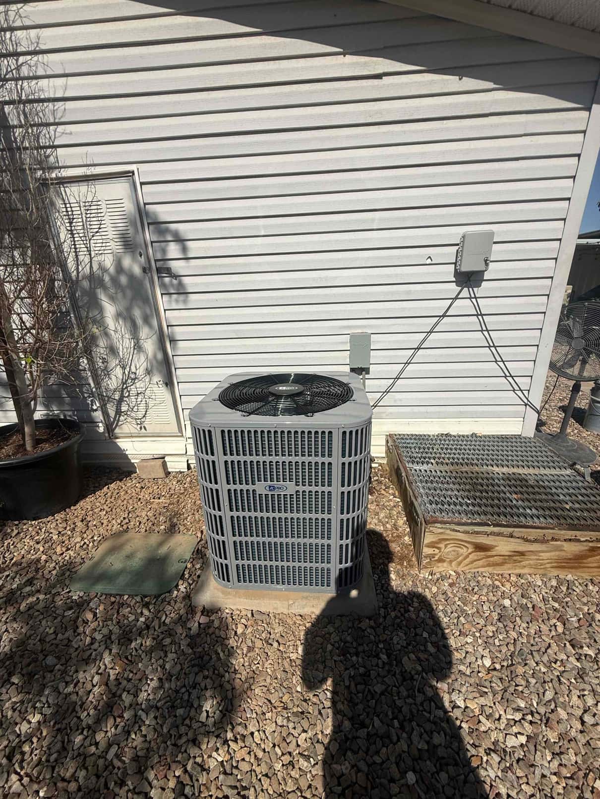 New outdoor condenser set on a level pad with electrical disconnect mounted on the wall and tidy line routing.