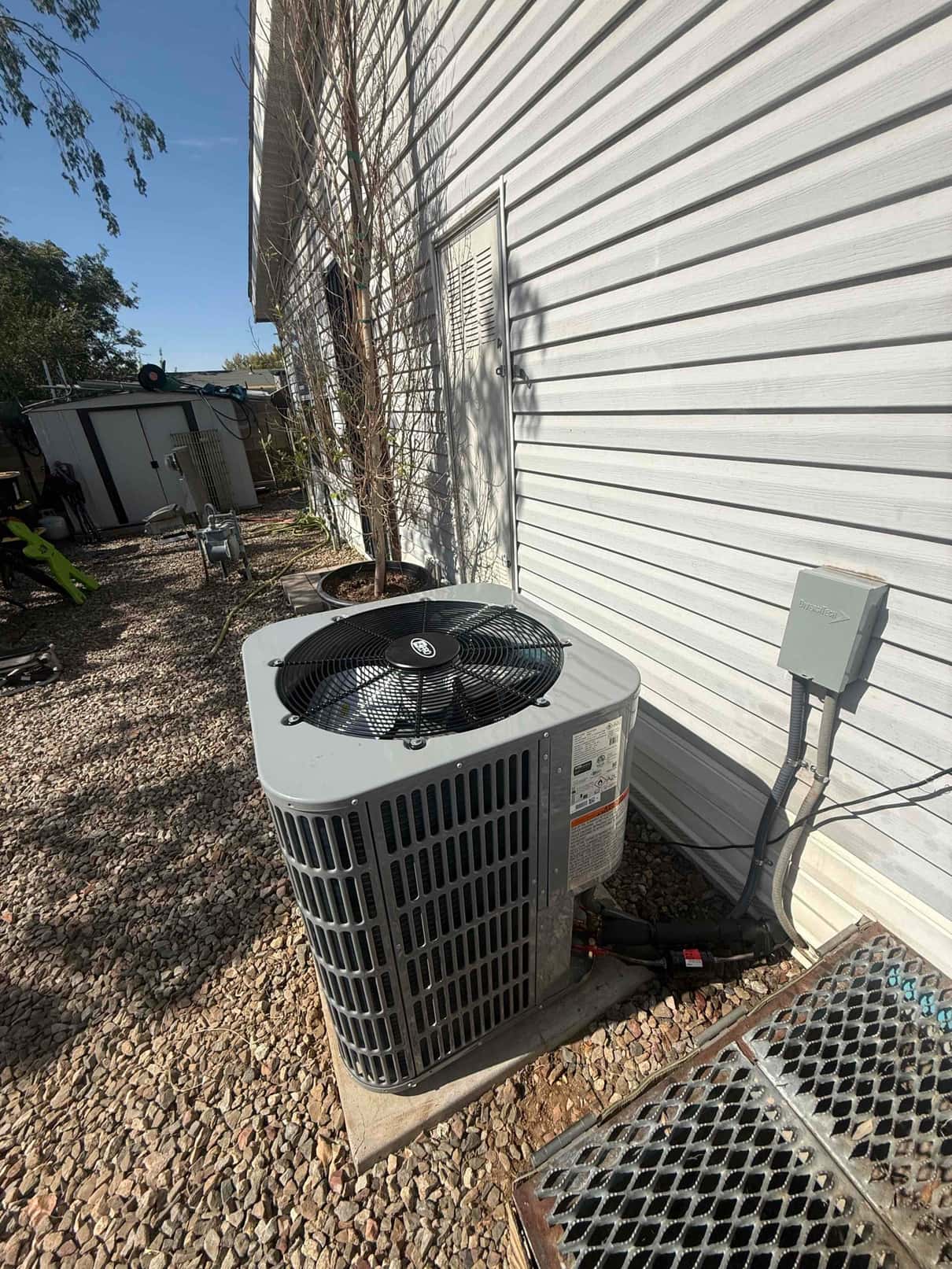 New outdoor condenser set on a level pad with insulated line set and weatherproof electrical disconnect mounted nearby.