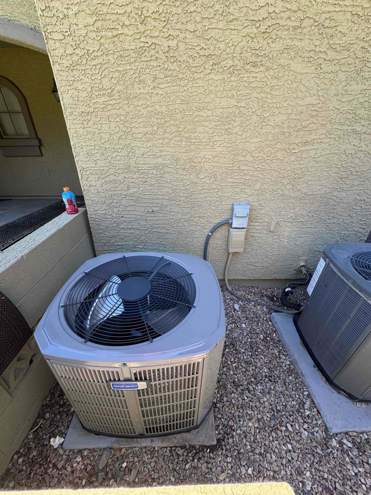 New outdoor heat pump condenser set on a level pad with electrical disconnect and insulated line set adjacent to existing unit.