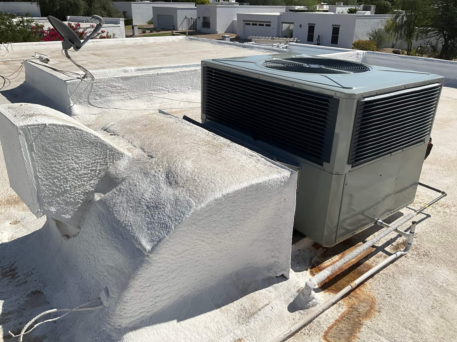 New rooftop package HVAC unit installed on a flat roof with sealed curb, insulated condensate drain, and refrigerant line routing.