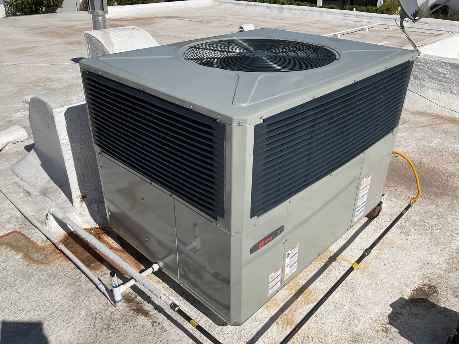 New rooftop package HVAC unit set on curb with condensate drain and gas piping connected, ready for commissioning.