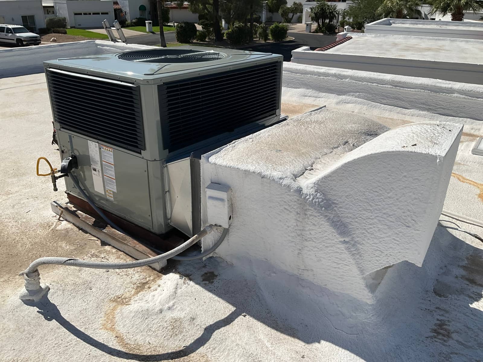 New rooftop package unit set on curb with sealed roof penetration, flexible electrical conduit, and condensate drain routed across the roof.