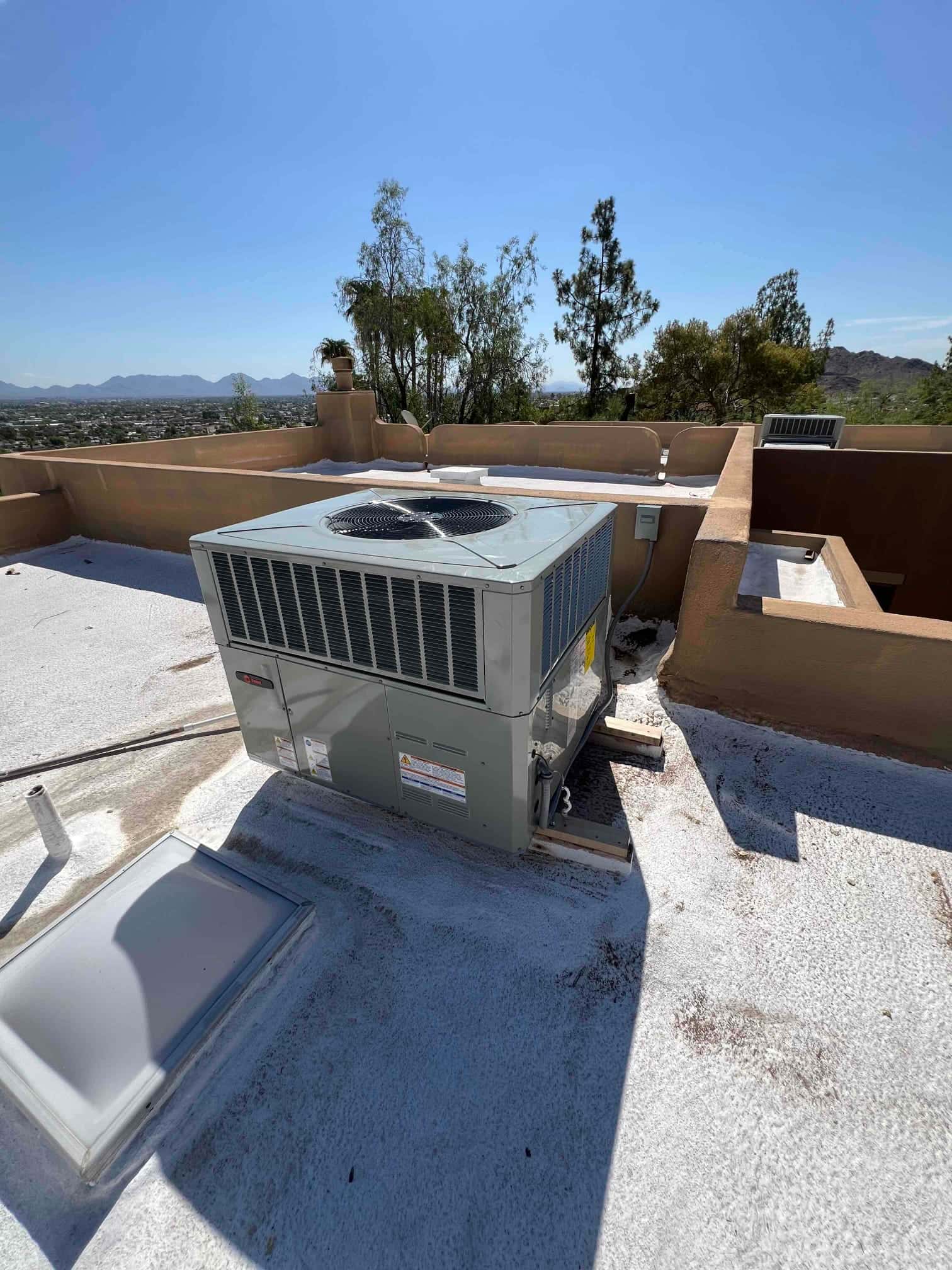 New rooftop packaged HVAC unit installed on blocks with sealed roof penetration and nearby electrical disconnect.