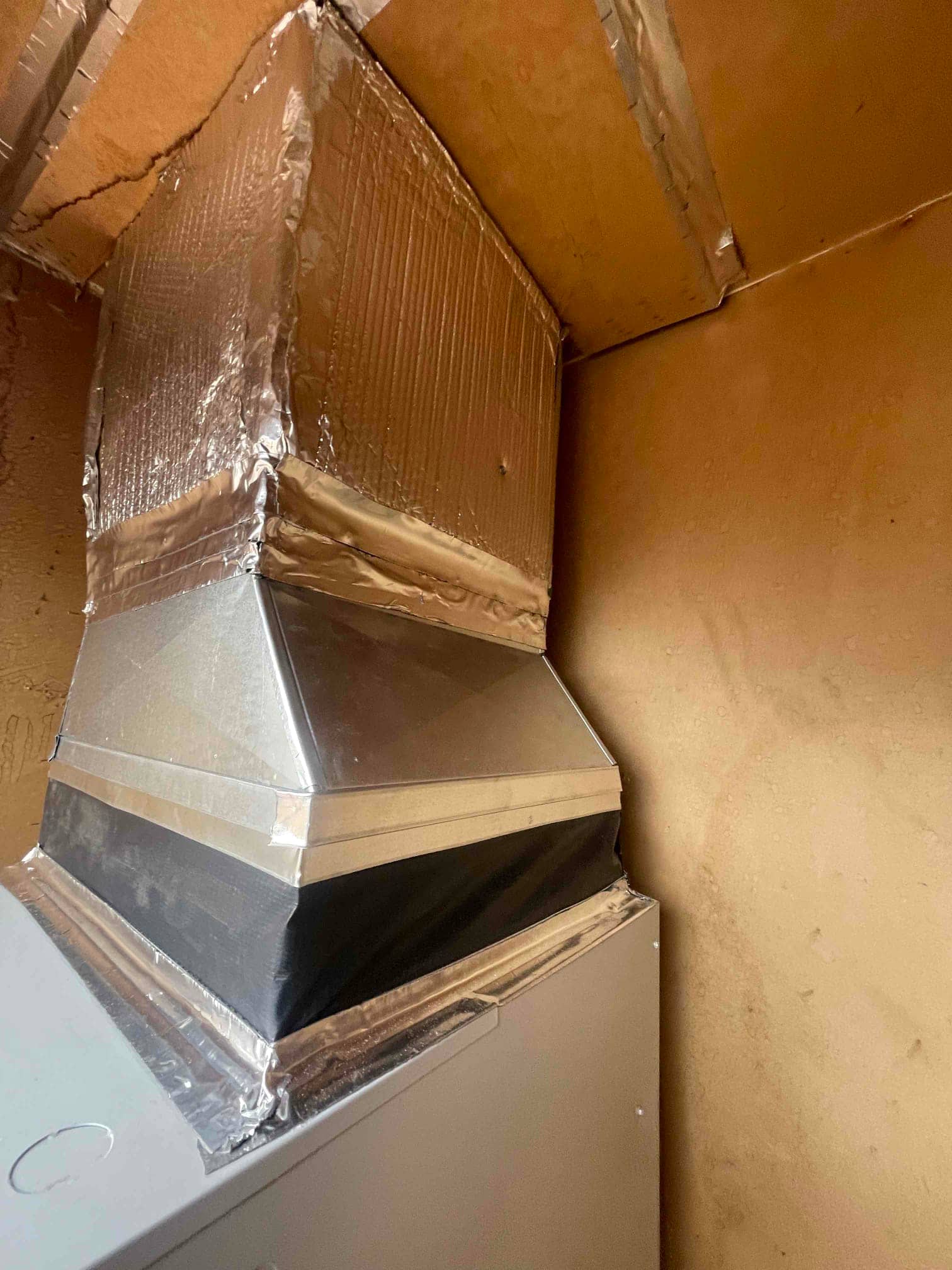 New supply plenum and transition sealed with foil tape on the air handler, showing insulated duct connection and clean fabrication.
