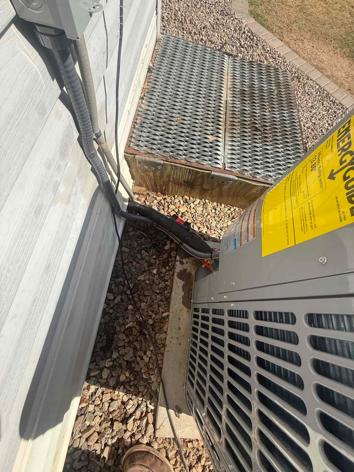 Outdoor condenser set on a concrete pad with insulated line set, electrical whip, and disconnect conduit secured along the wall.