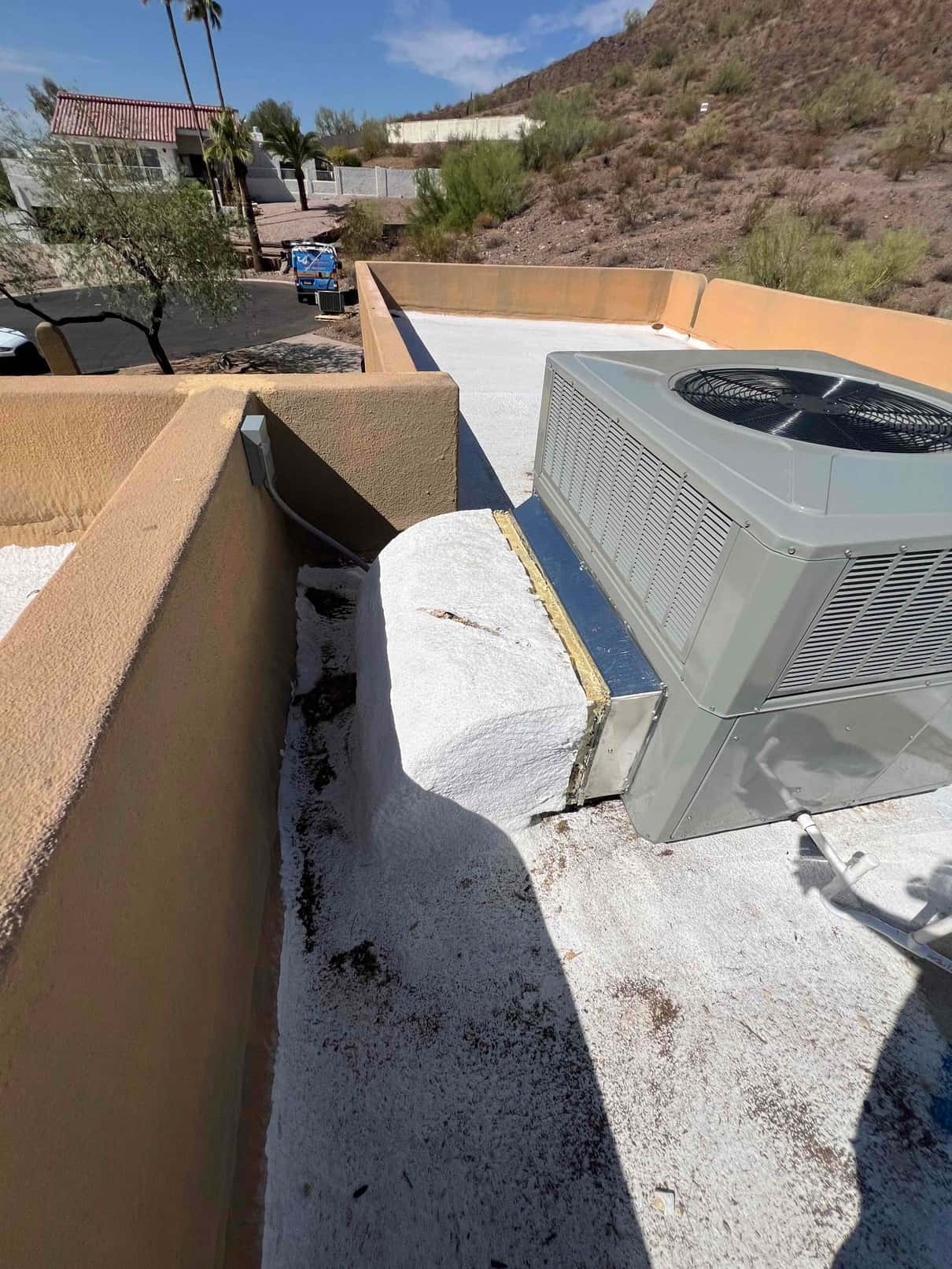 Rooftop package heat pump set on a coated roof with sealed curb and connected refrigerant and electrical lines.