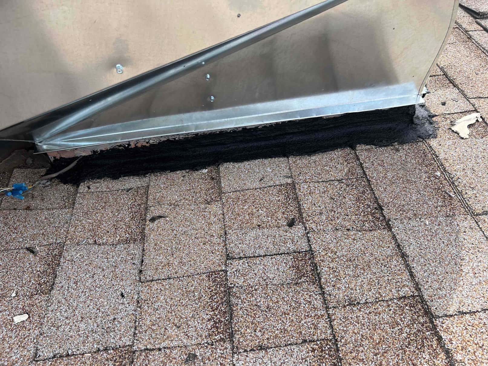 Rooftop package unit curb flashing sealed with roofing mastic at the base to weatherproof the penetration.