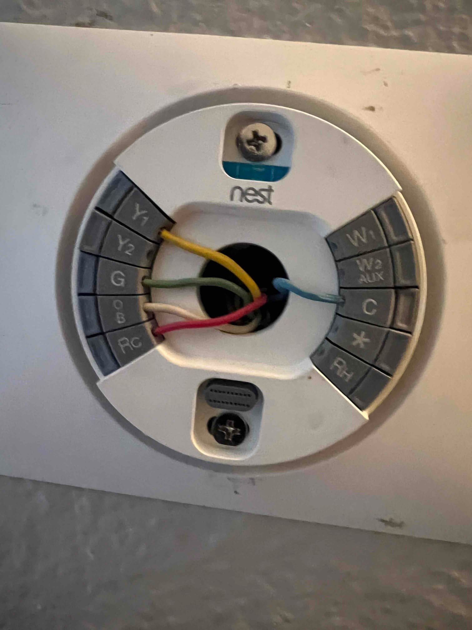 Thermostat base with control wires connected to terminals including Y1, G, RC, W, and C during installation.