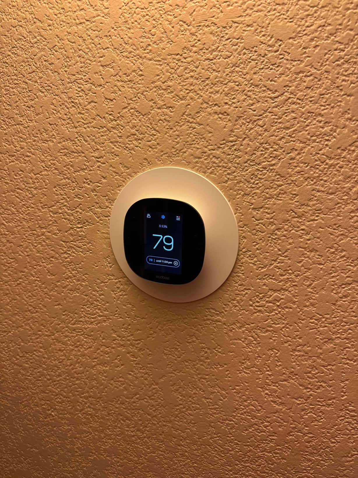 Wall-mounted smart thermostat displays indoor temperature at 79 degrees with system status shown on the screen.