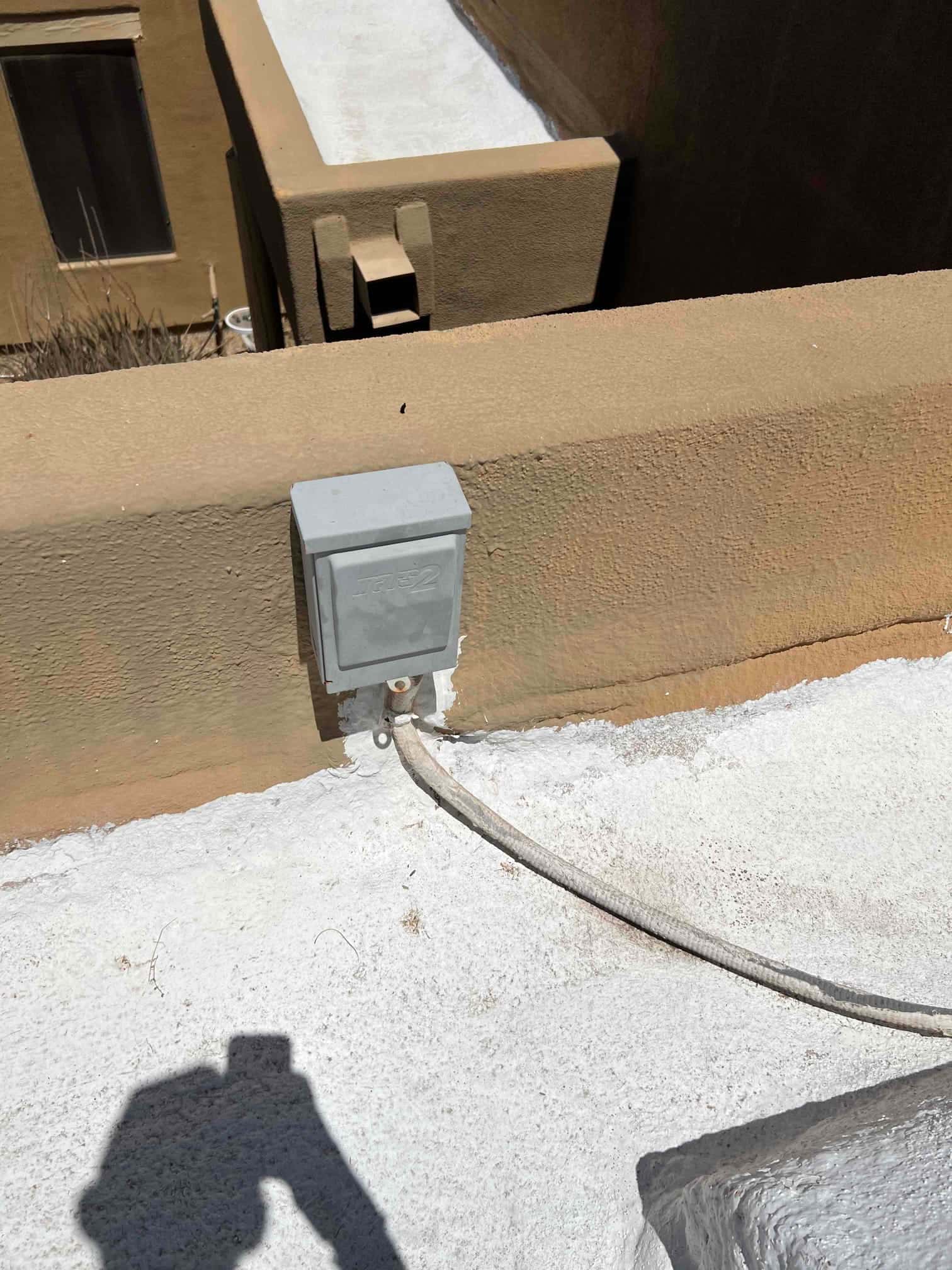 Weatherproof electrical disconnect mounted on rooftop wall with armored conduit routed to the HVAC condenser location.