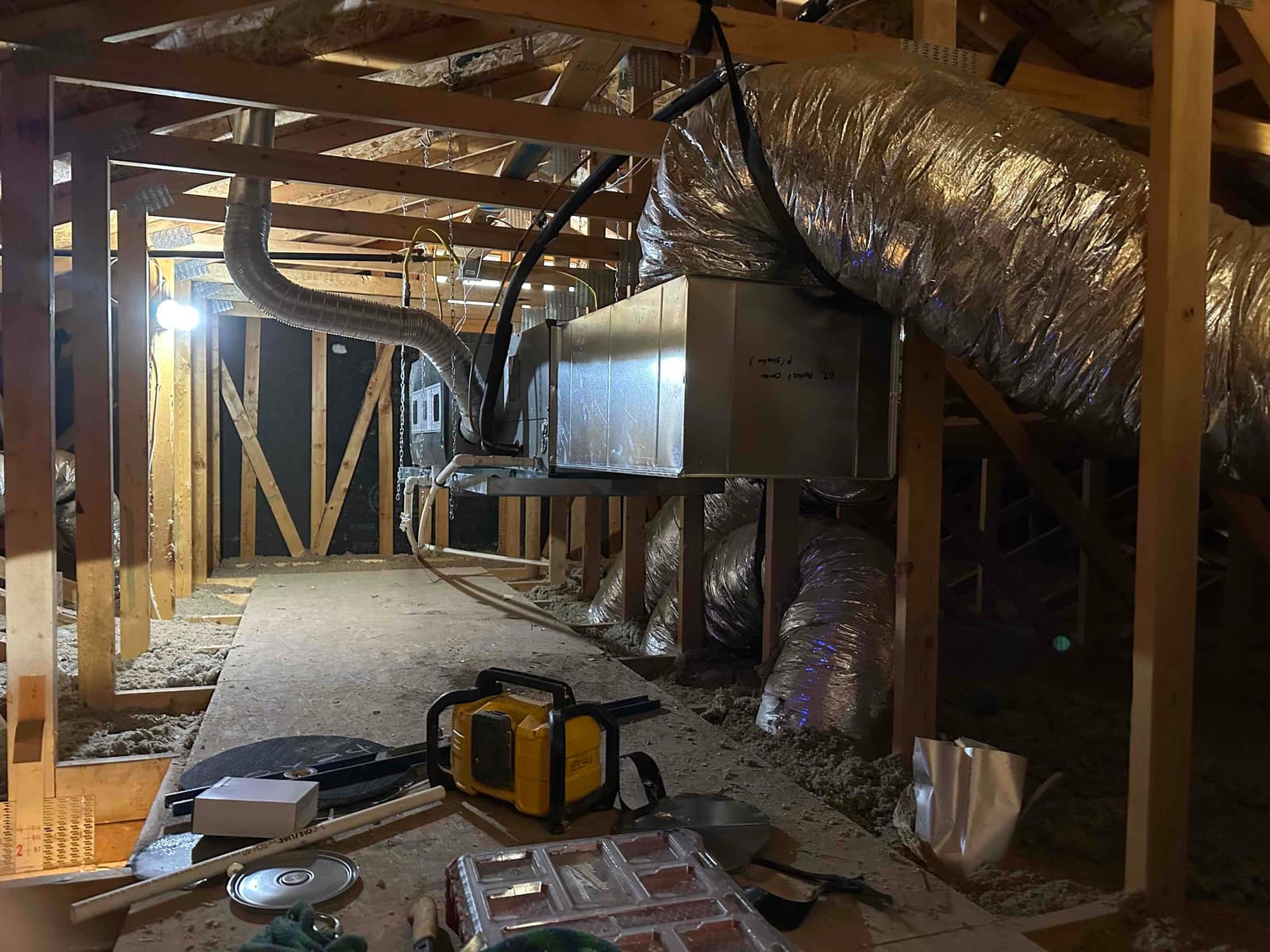 Air handler installed on a platform in the attic with insulated flex ducts, drain line, and electrical whip connected.