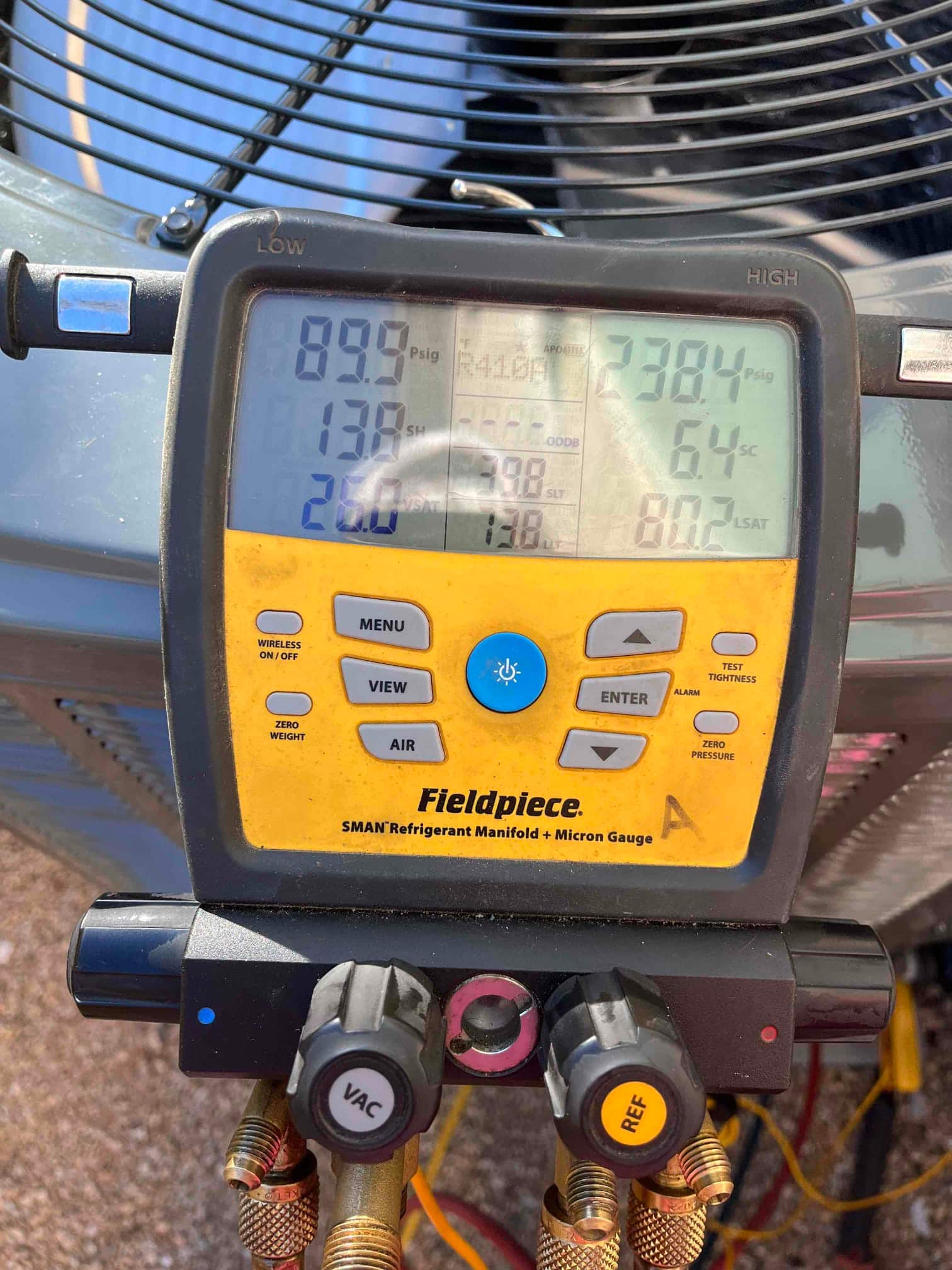 Digital manifold connected at the condenser shows operating pressures and calculated superheat and subcooling during system commissioning.