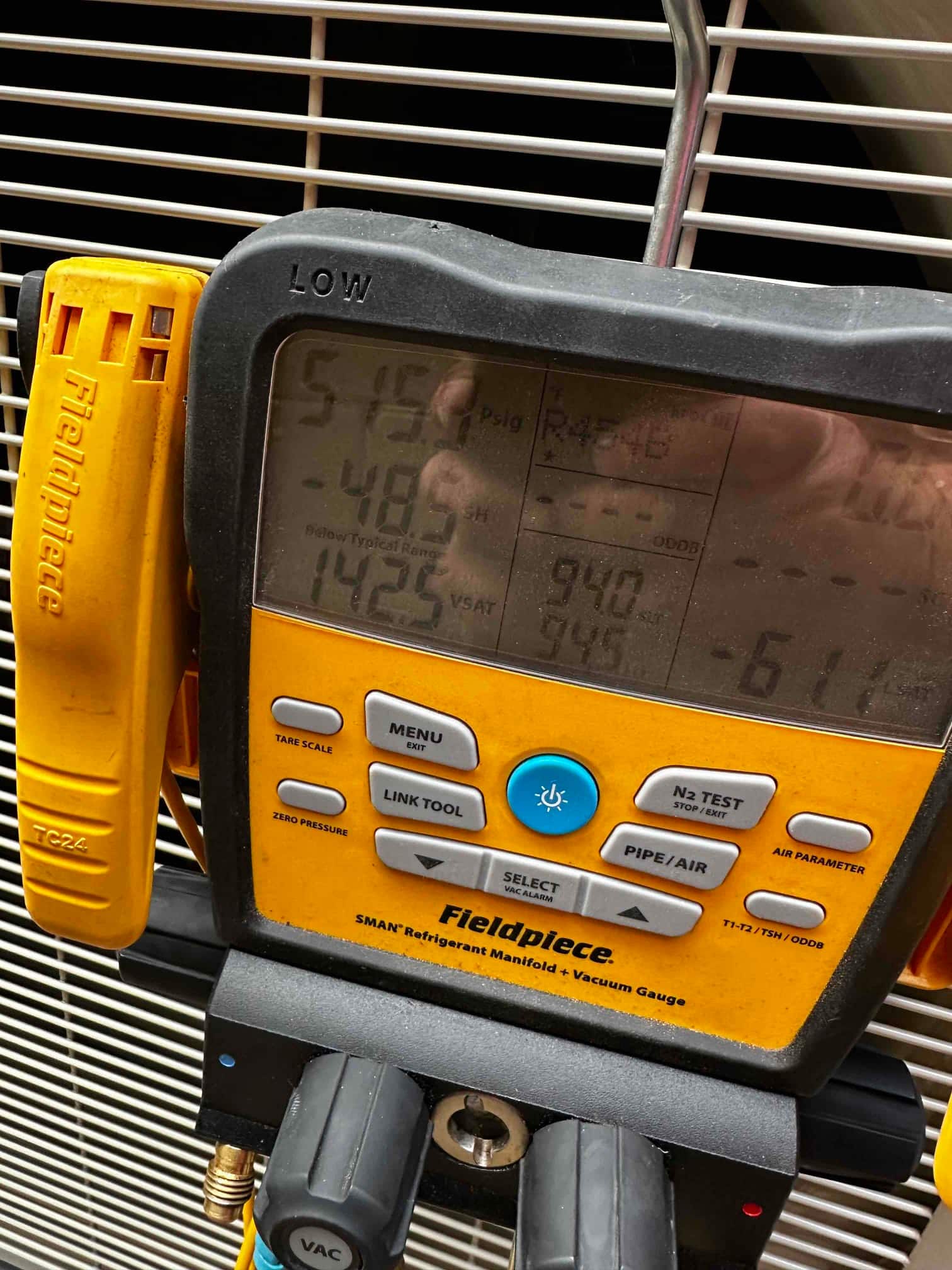 Digital manifold connected to the outdoor unit displays operating suction and liquid pressures with refrigerant type visible on the screen.