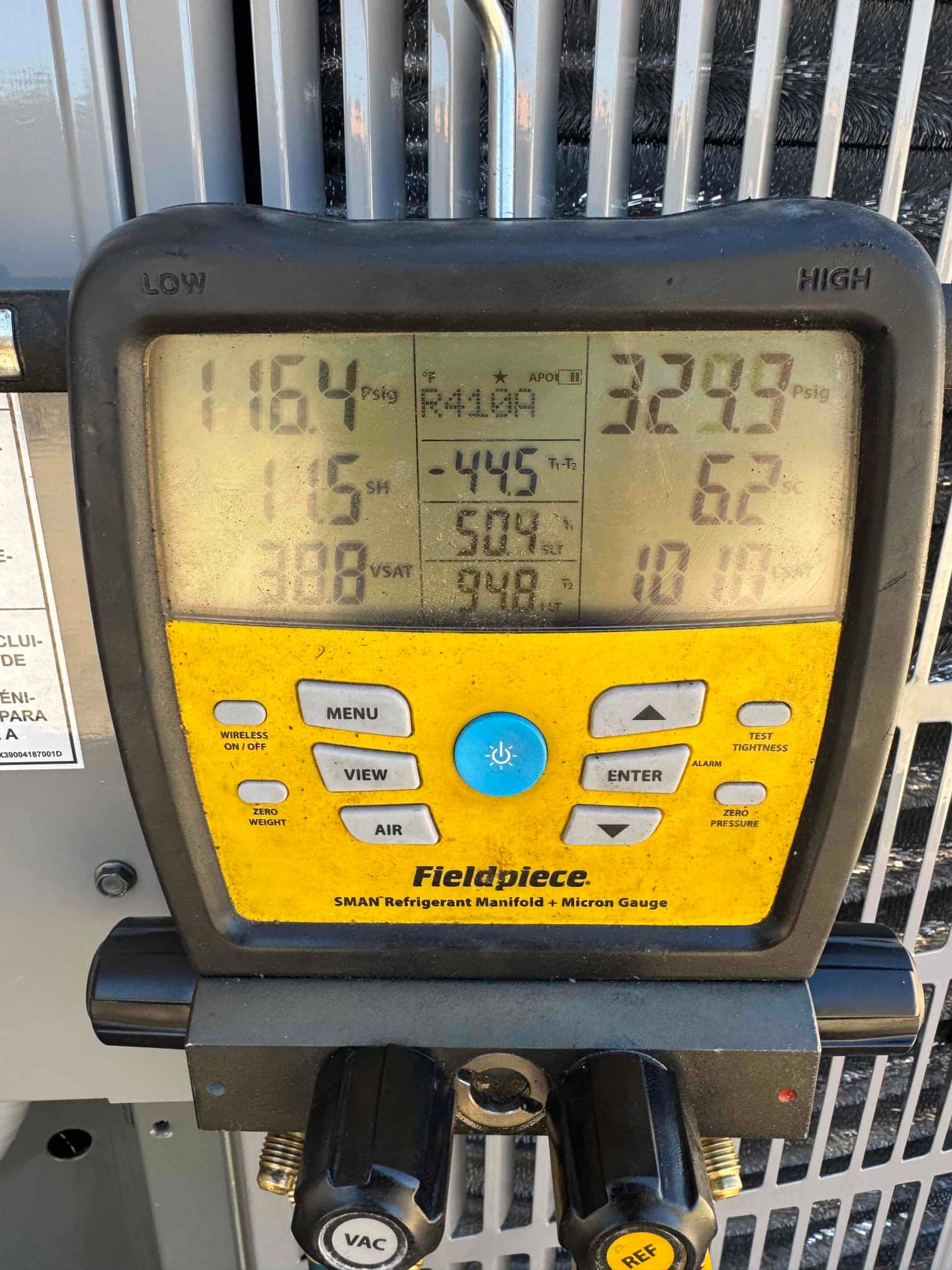 Digital manifold on the outdoor unit shows operating pressures with refrigerant, documenting suction and liquid sides during system commissioning.
