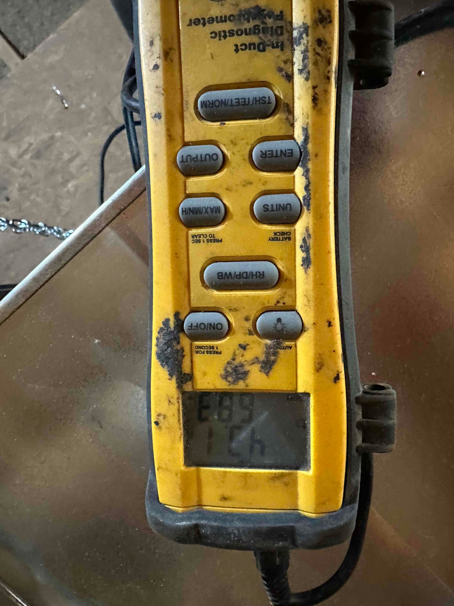 Digital thermometer with probe connected measures air temperature during duct temperature checks on the newly installed system.
