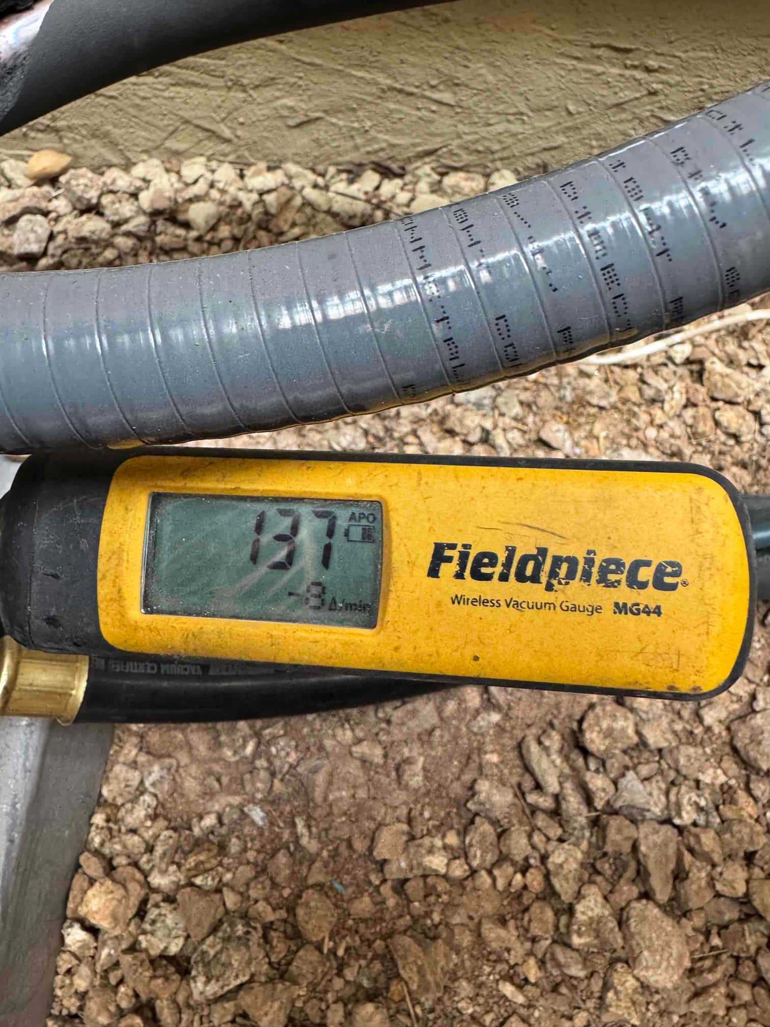 Micron gauge displays 137 microns during system evacuation, confirming a deep vacuum before introducing refrigerant.