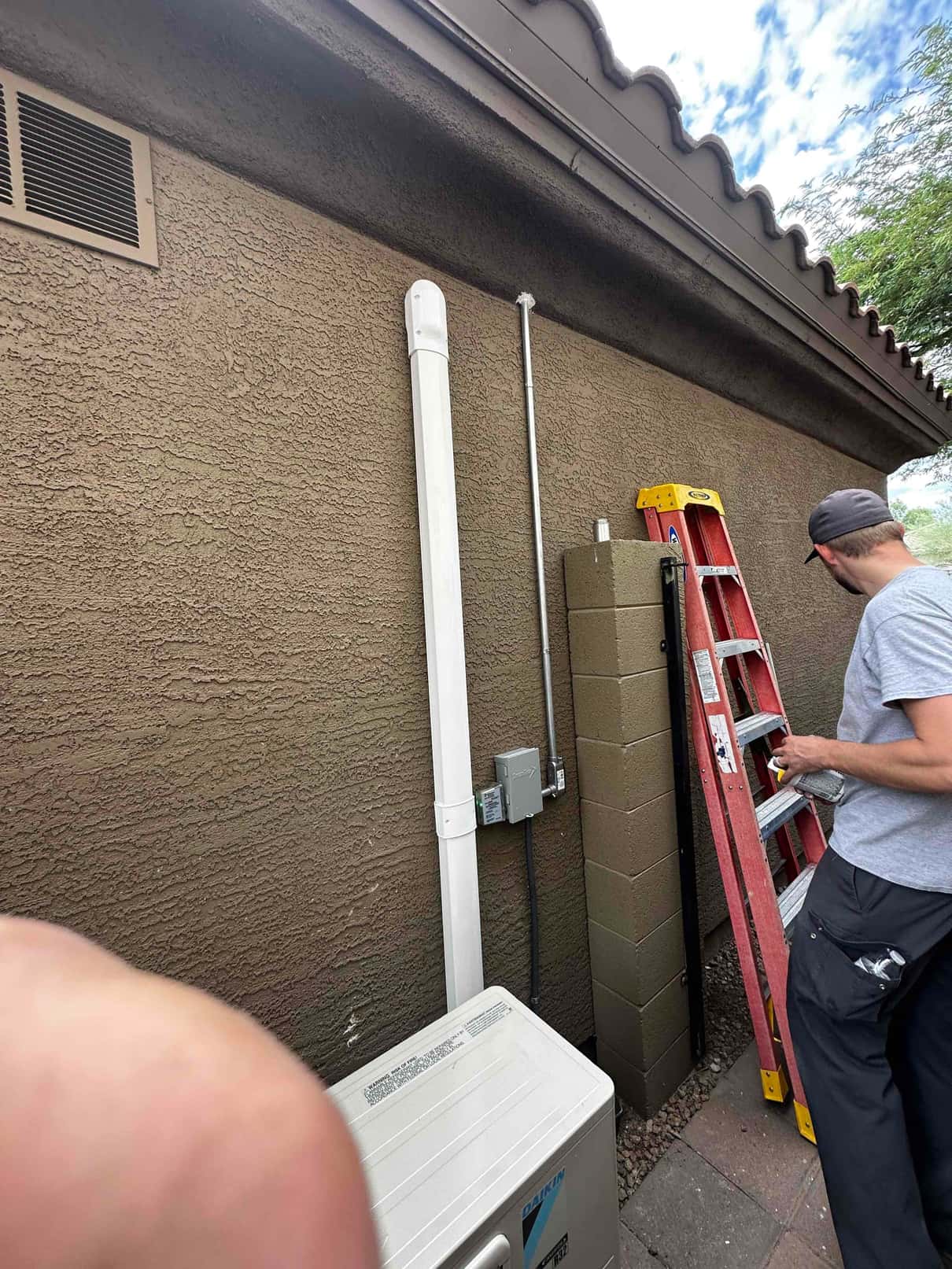 Mini-split outdoor unit installed with line set cover, weatherproof disconnect, and neatly routed electrical conduit along the exterior wall.