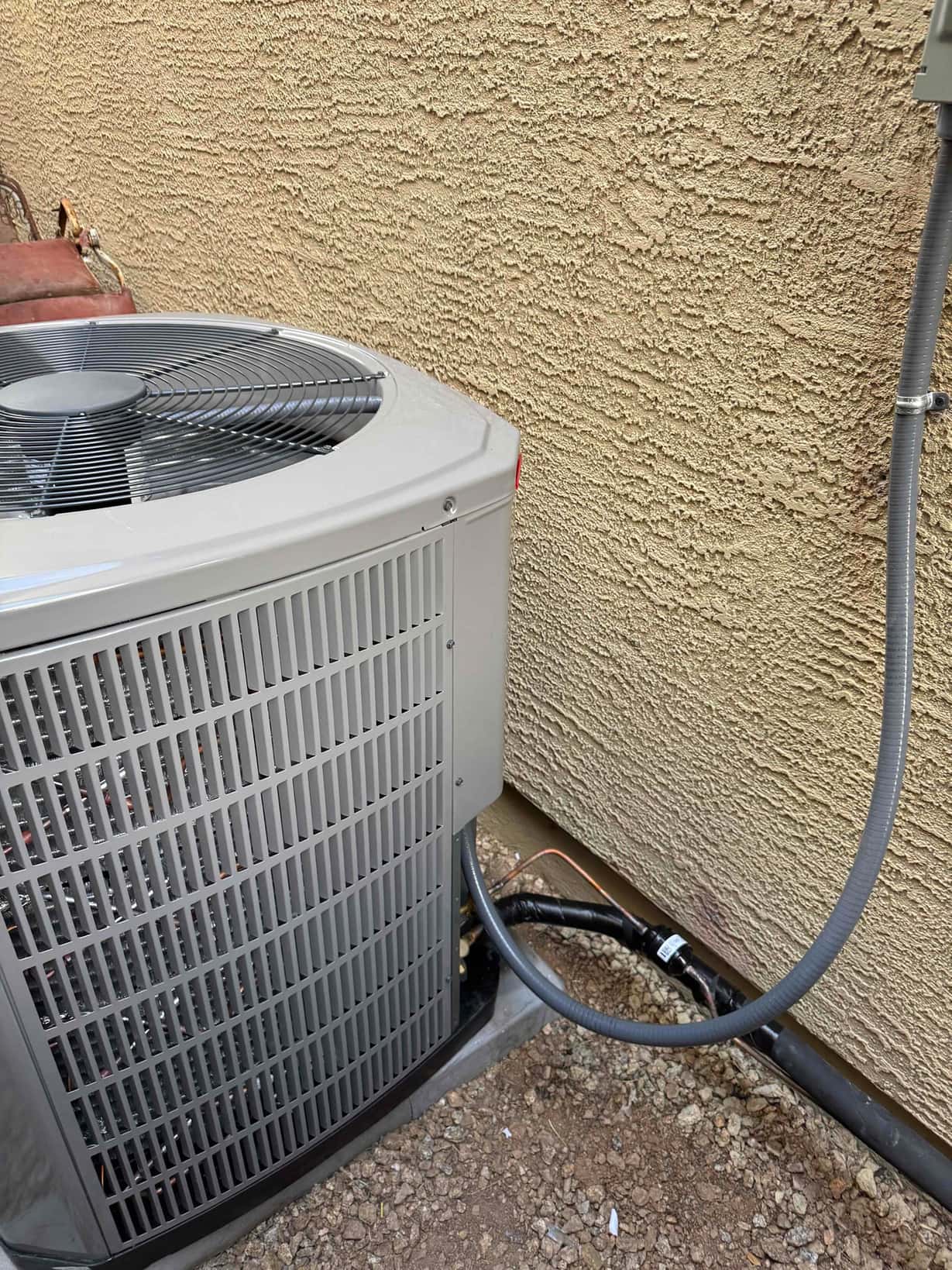 Outdoor condenser set on a level pad with insulated refrigerant lines and electrical whip routed to the disconnect.
