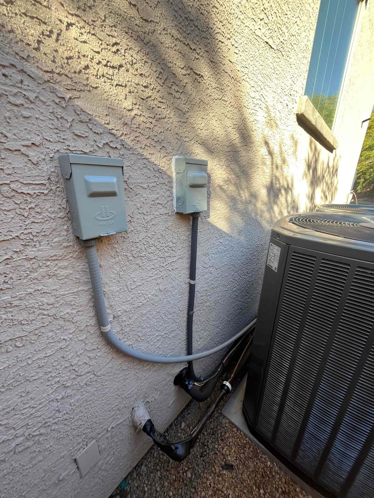 Outdoor condenser set on a pad with new electrical disconnects, sealed wall penetrations, and insulated refrigerant and condensate lines routed neatly.