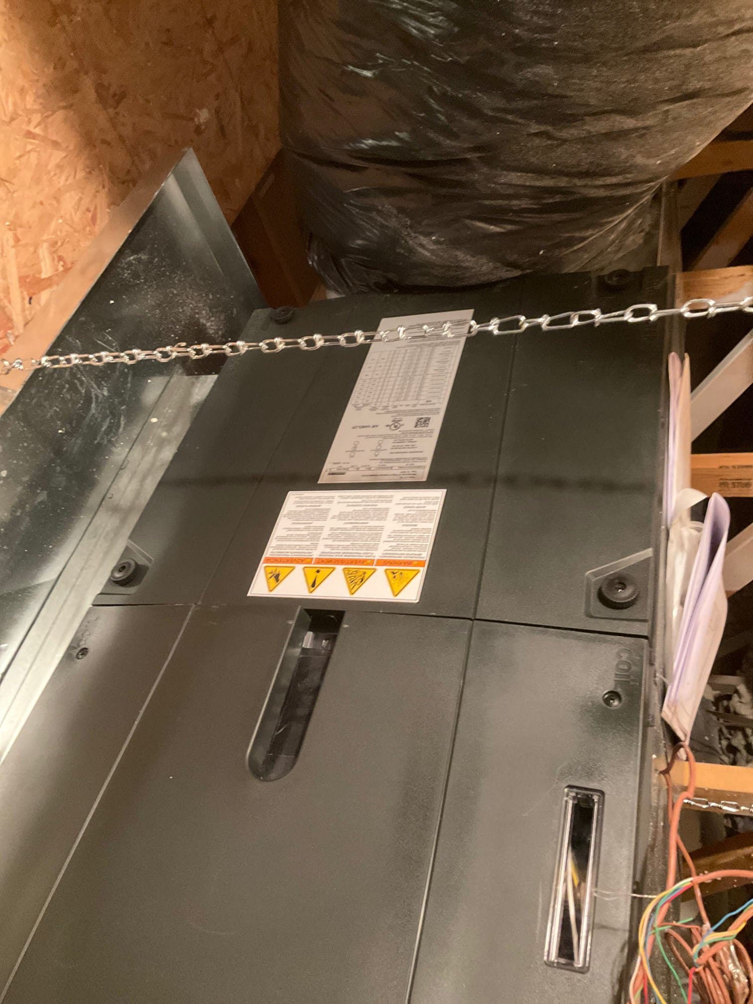 Suspended air handler installed with insulated duct connection and service access panels secured in the attic space.