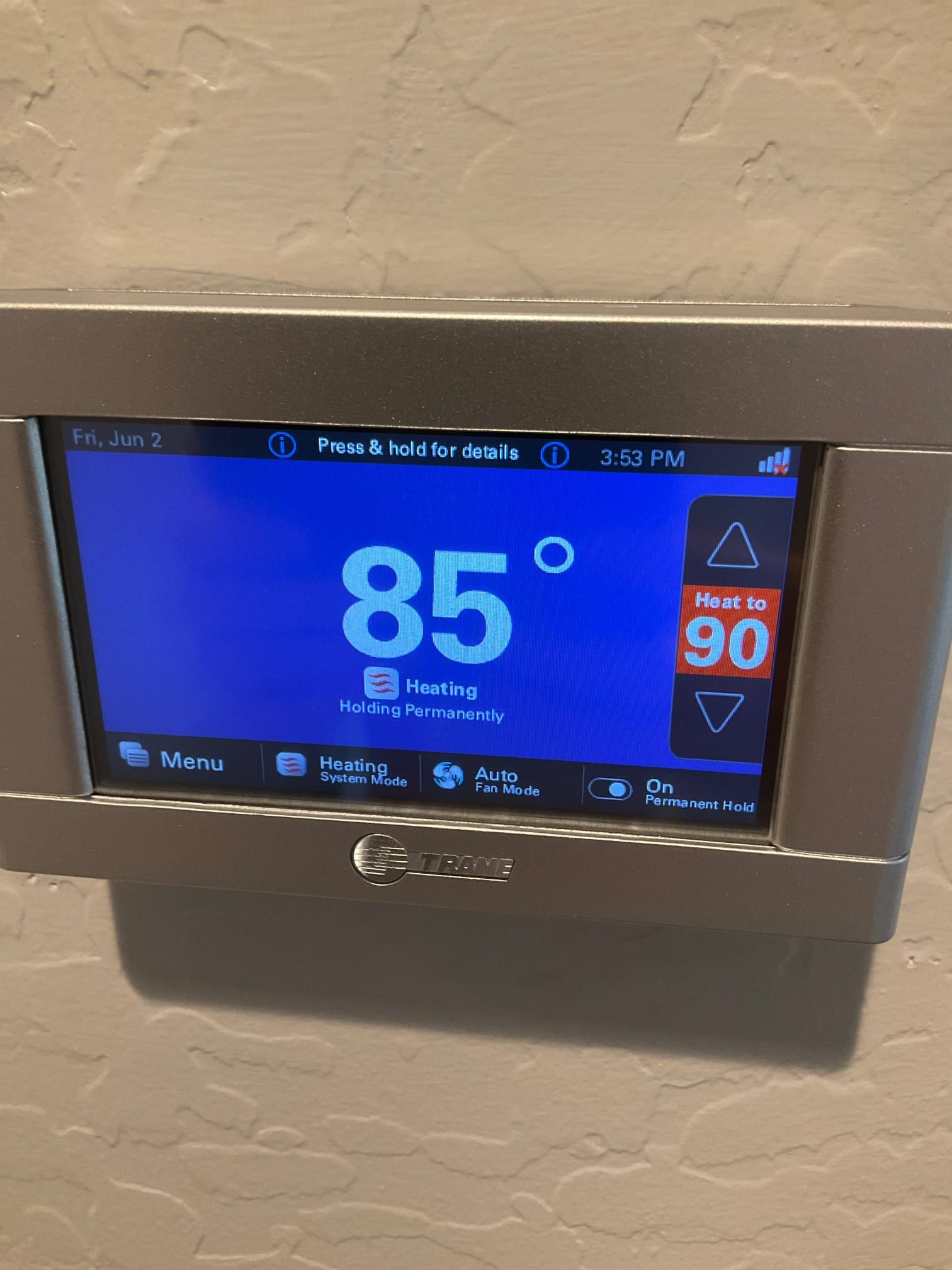 Wall-mounted thermostat display shows 85 degrees with system in heating mode and permanent hold enabled.