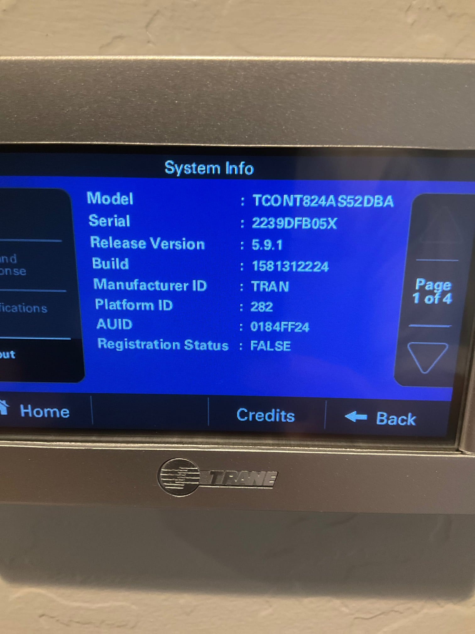 Wall-mounted thermostat displays system information screen during post-install setup, showing model, serial, and software version details.