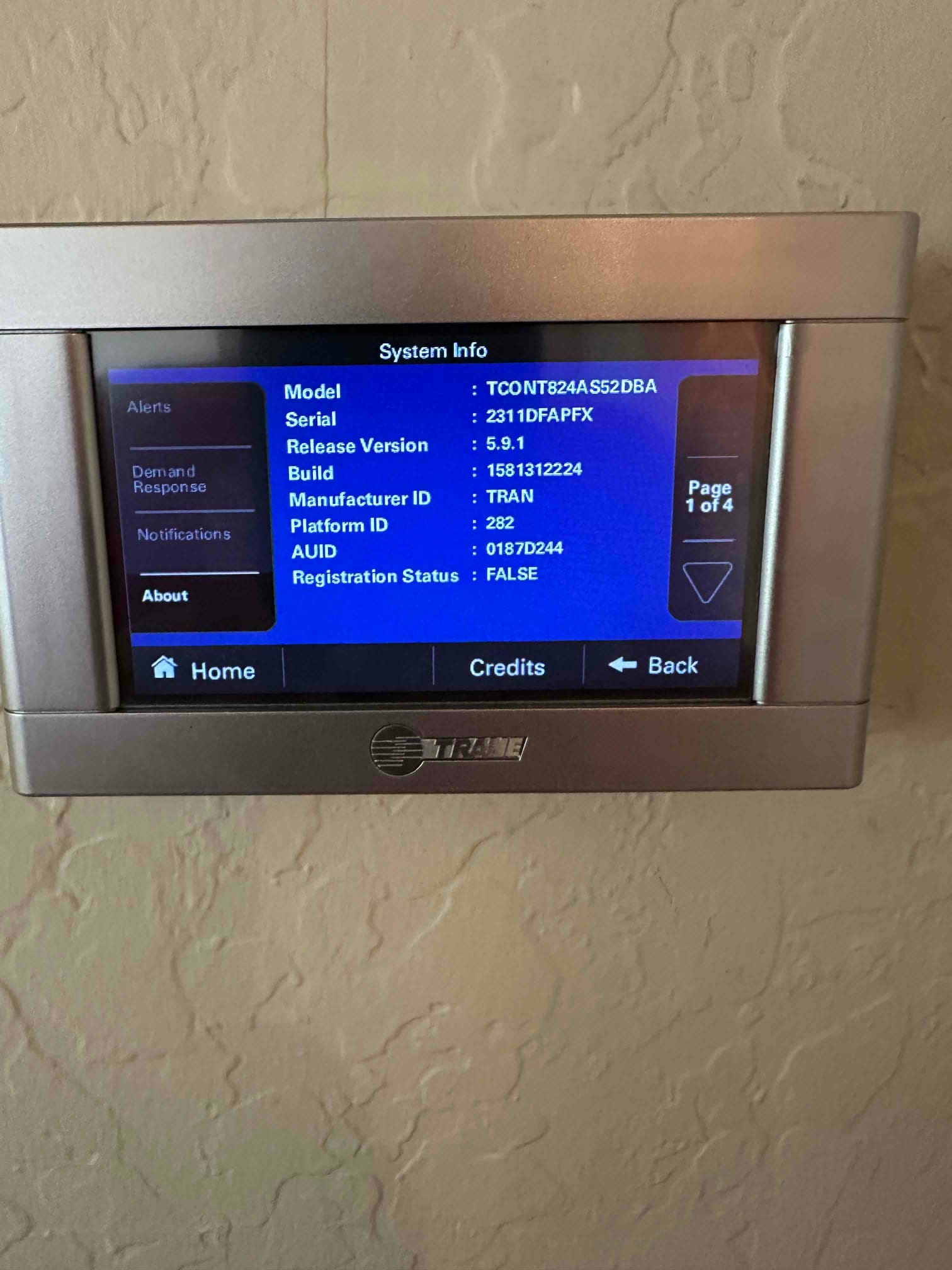 Wall-mounted touchscreen thermostat displays system information menu during setup after installation.