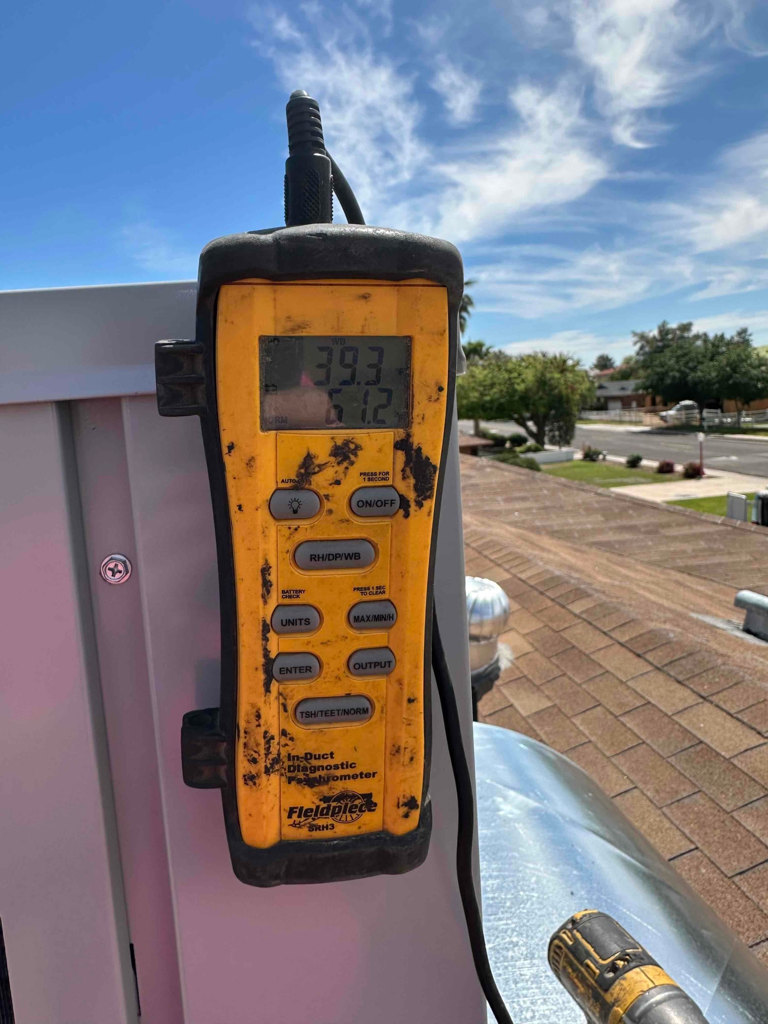 Digital psychrometer displays wet-bulb and dry-bulb readings during air-side checks on the rooftop HVAC installation.