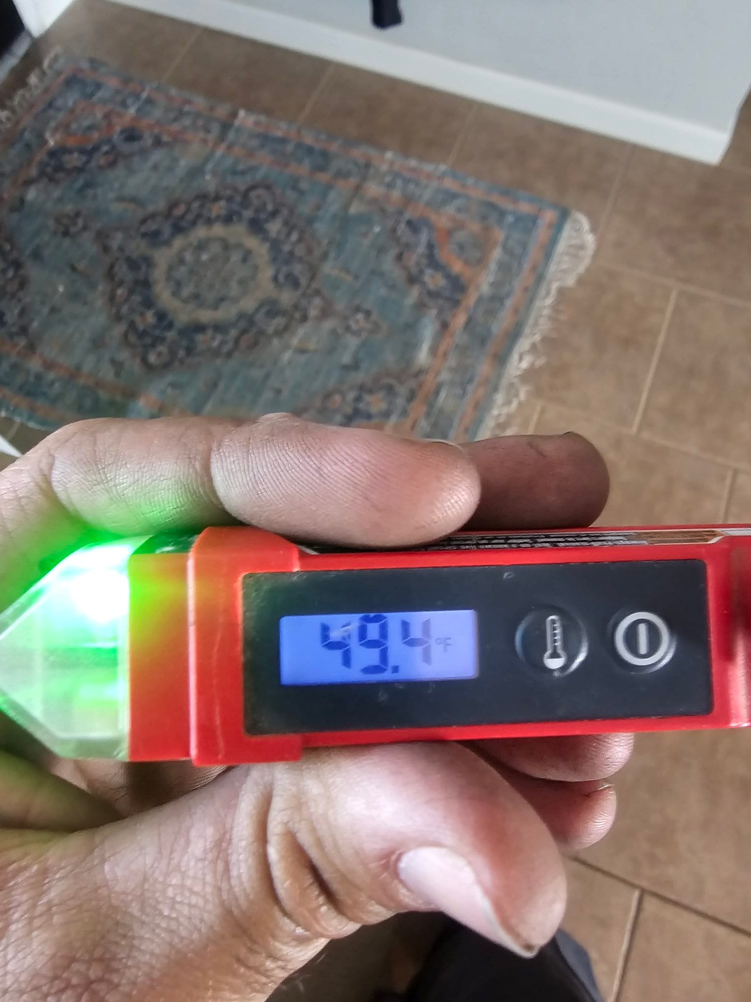 Digital thermometer displays 49.4°F while measuring conditioned air during system airflow verification.