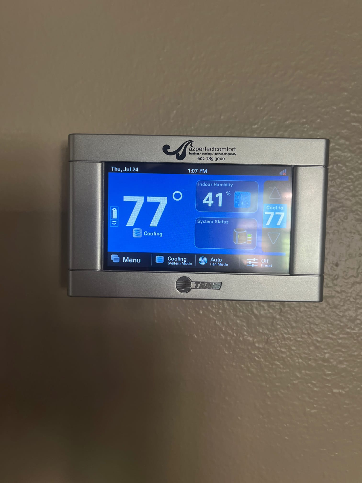 Digital thermostat display shows indoor temperature at 77°F with cooling active and system status indicators visible.