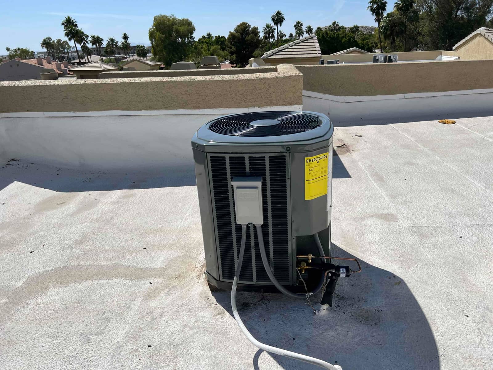 New outdoor condenser set on a flat rooftop with connected refrigerant lines, insulated suction line, and electrical whip installed.