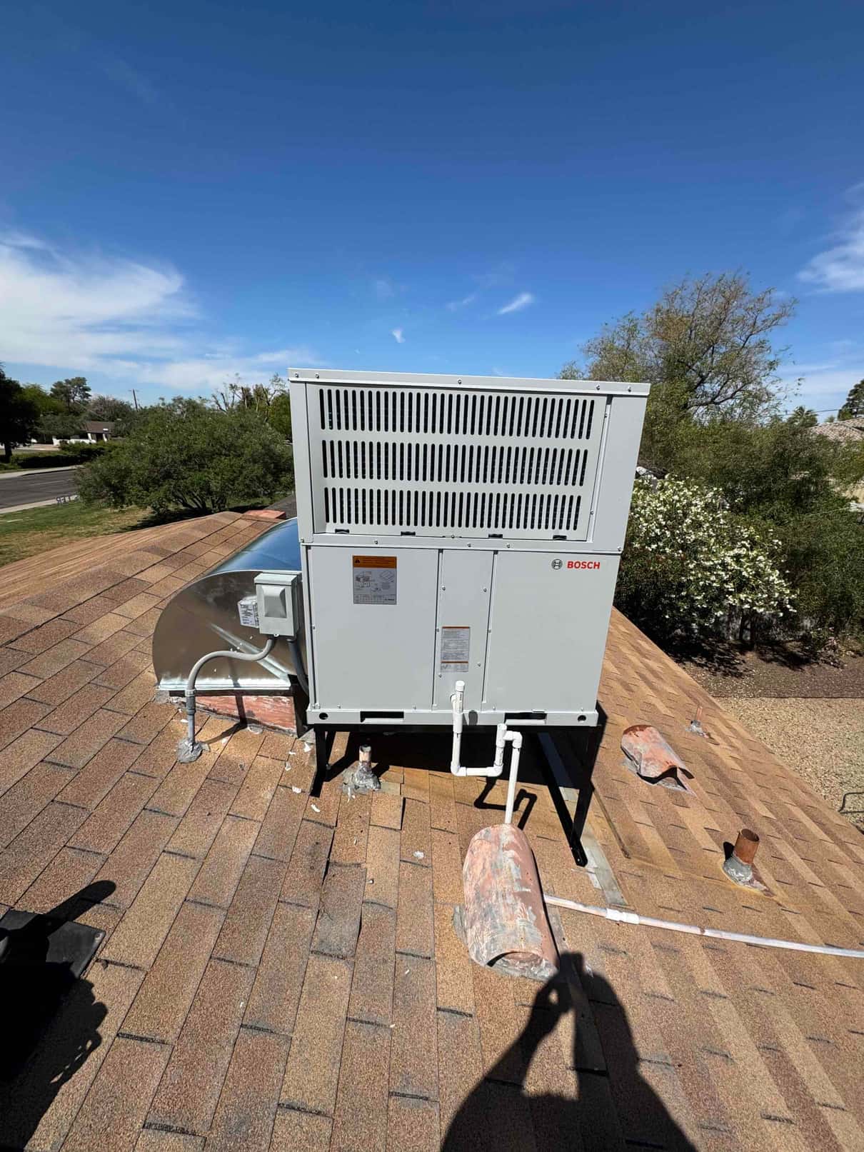 New packaged heat pump set on a rooftop stand with sealed duct curb, electrical whip, and insulated condensate drain.