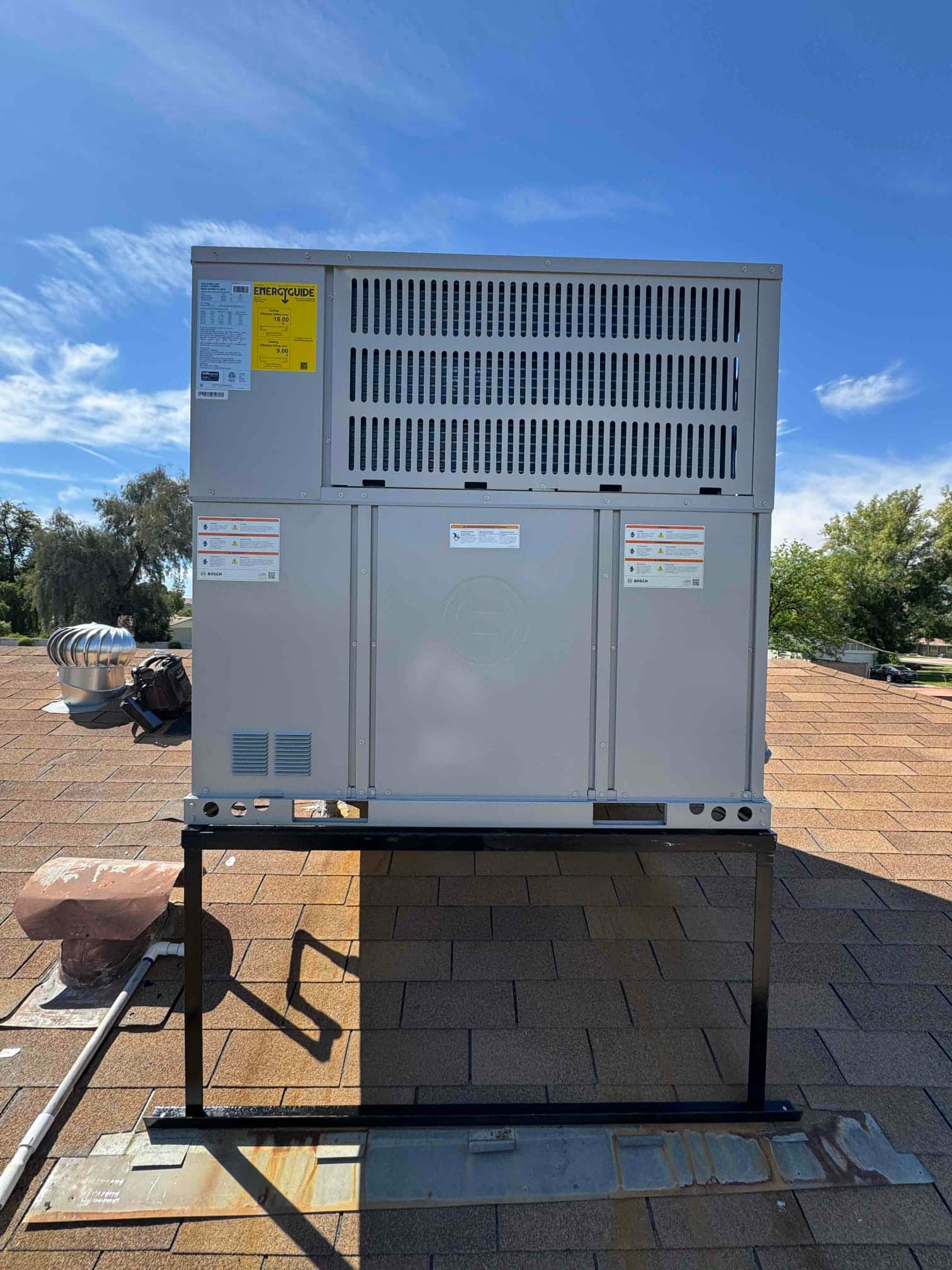 New packaged heat pump set on a rooftop stand with sealed roof curb and visible service clearances.