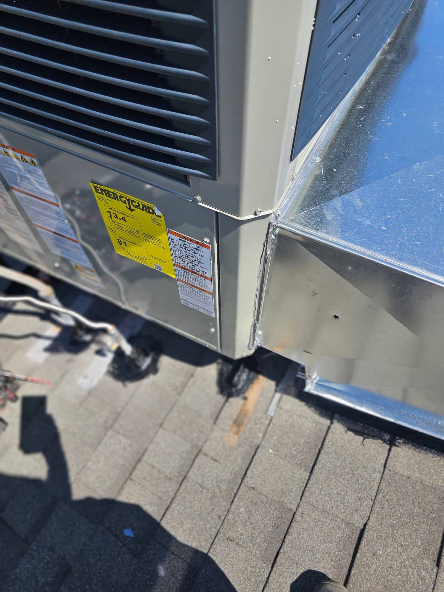New rooftop package unit set and connected to sheet metal duct transition, with roof penetrations sealed around refrigerant and electrical entries.