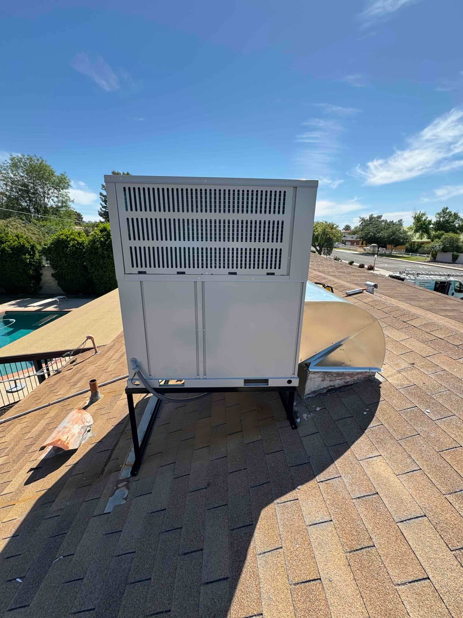 New rooftop packaged unit set on a metal stand with duct transition connected and flexible electrical conduit routed.