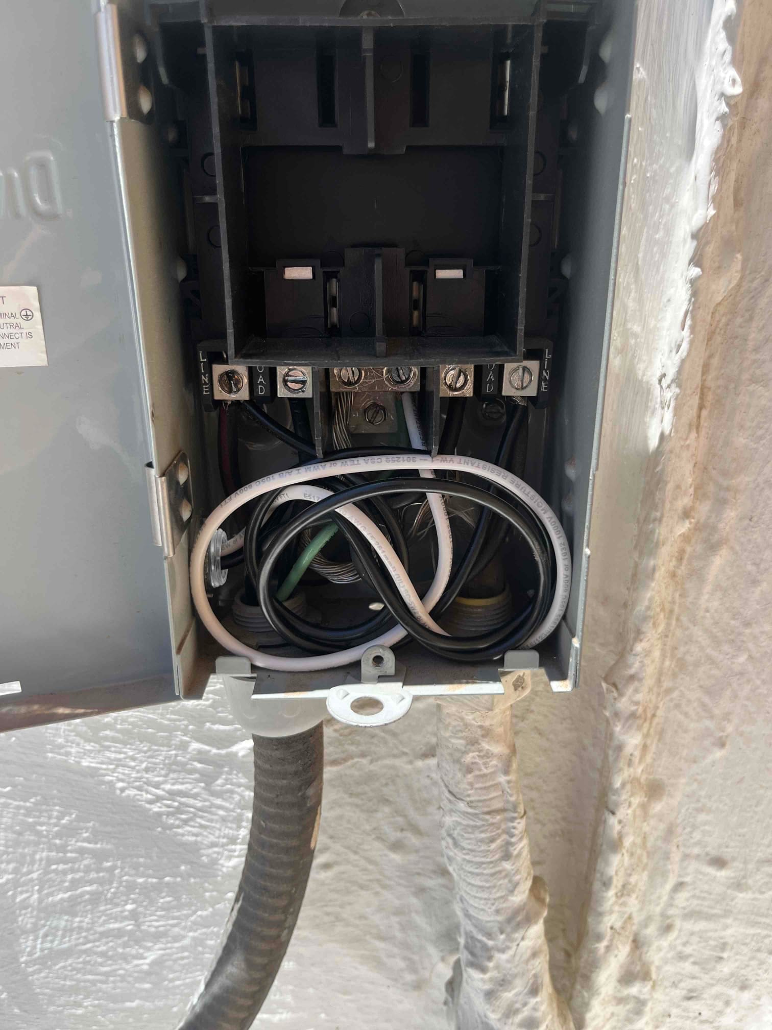 Outdoor HVAC disconnect box open, showing neatly routed conductors and installed surge protector wiring inside the enclosure.