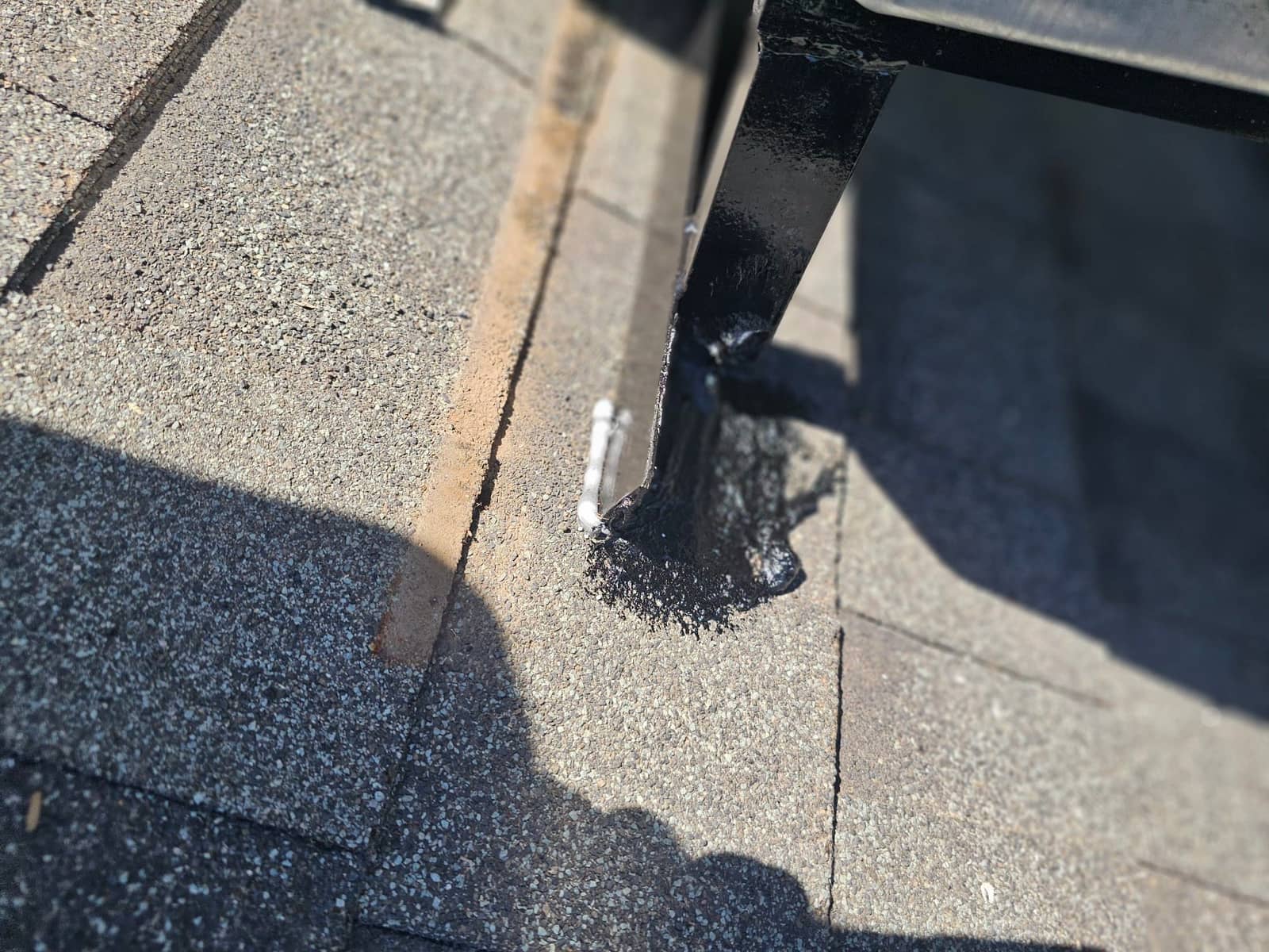 Roof unit support leg sealed to shingles with roofing mastic to weatherproof the mounting point on the new installation.