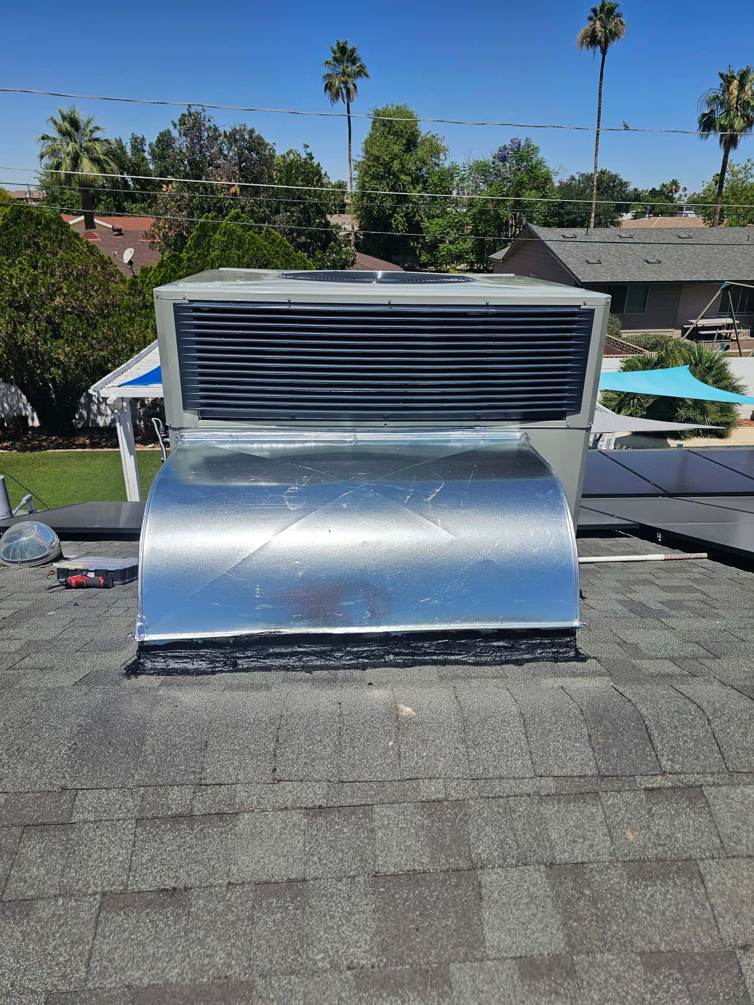 Rooftop package HVAC unit installed with new sealed curb and sheet-metal transition, set on shingle roof with clean flashing.