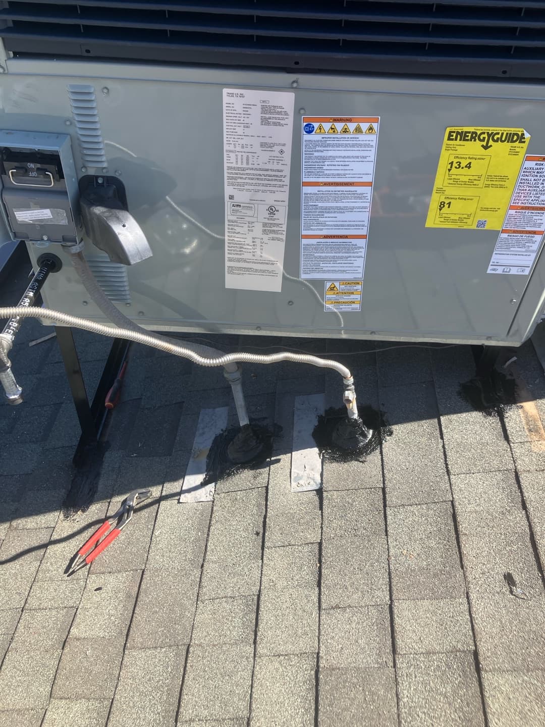 Rooftop package unit set with sealed roof penetrations, flex conduit to the disconnect, and drain piping visible alongside tools.