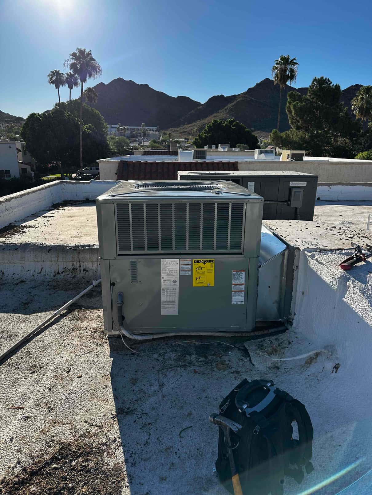 Rooftop packaged HVAC unit newly set on the curb with connected condensate drain and tools staged nearby.