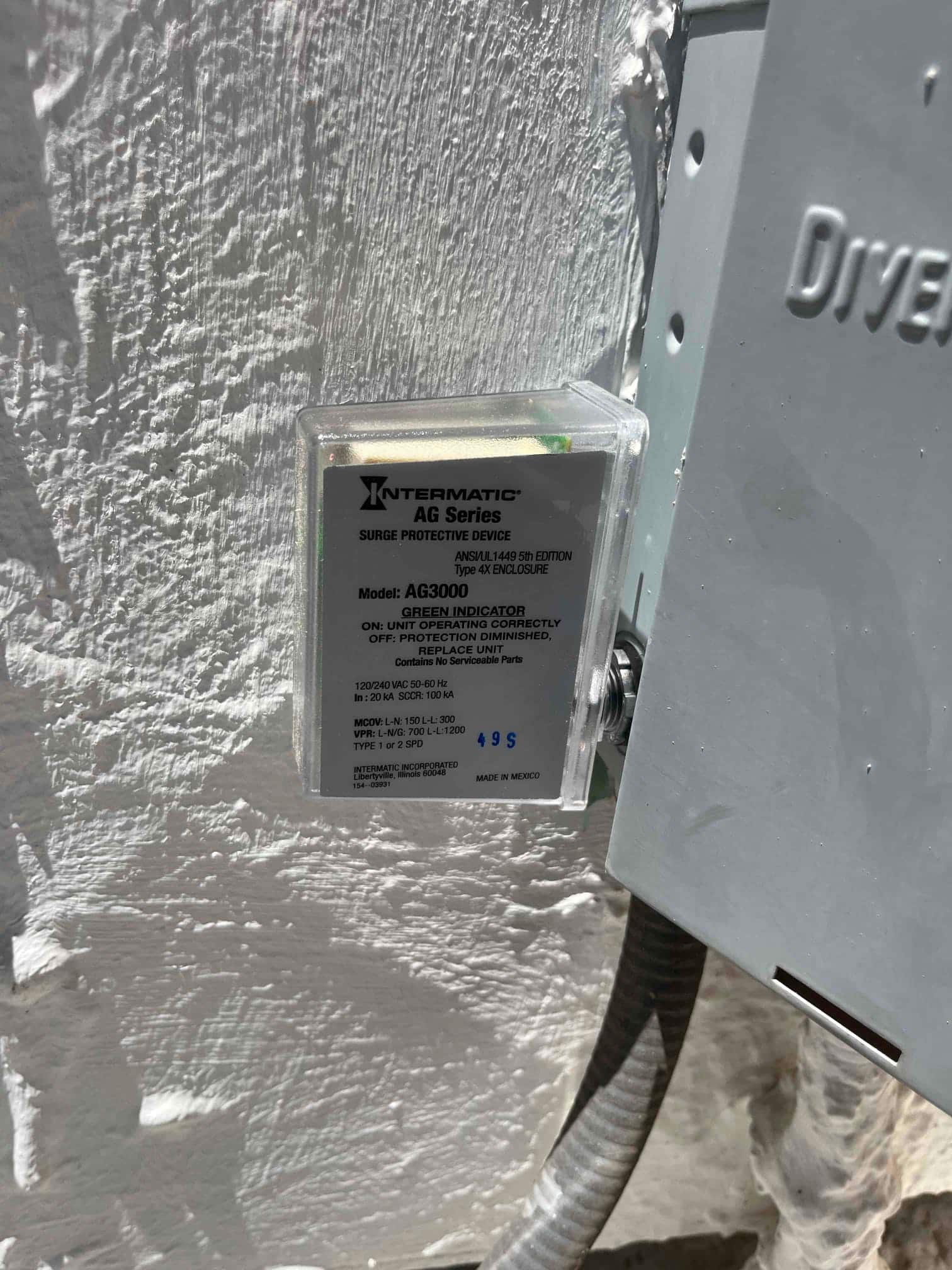Surge protective device installed next to an electrical disconnect, showing enclosed housing and conduit connection to the outdoor unit.