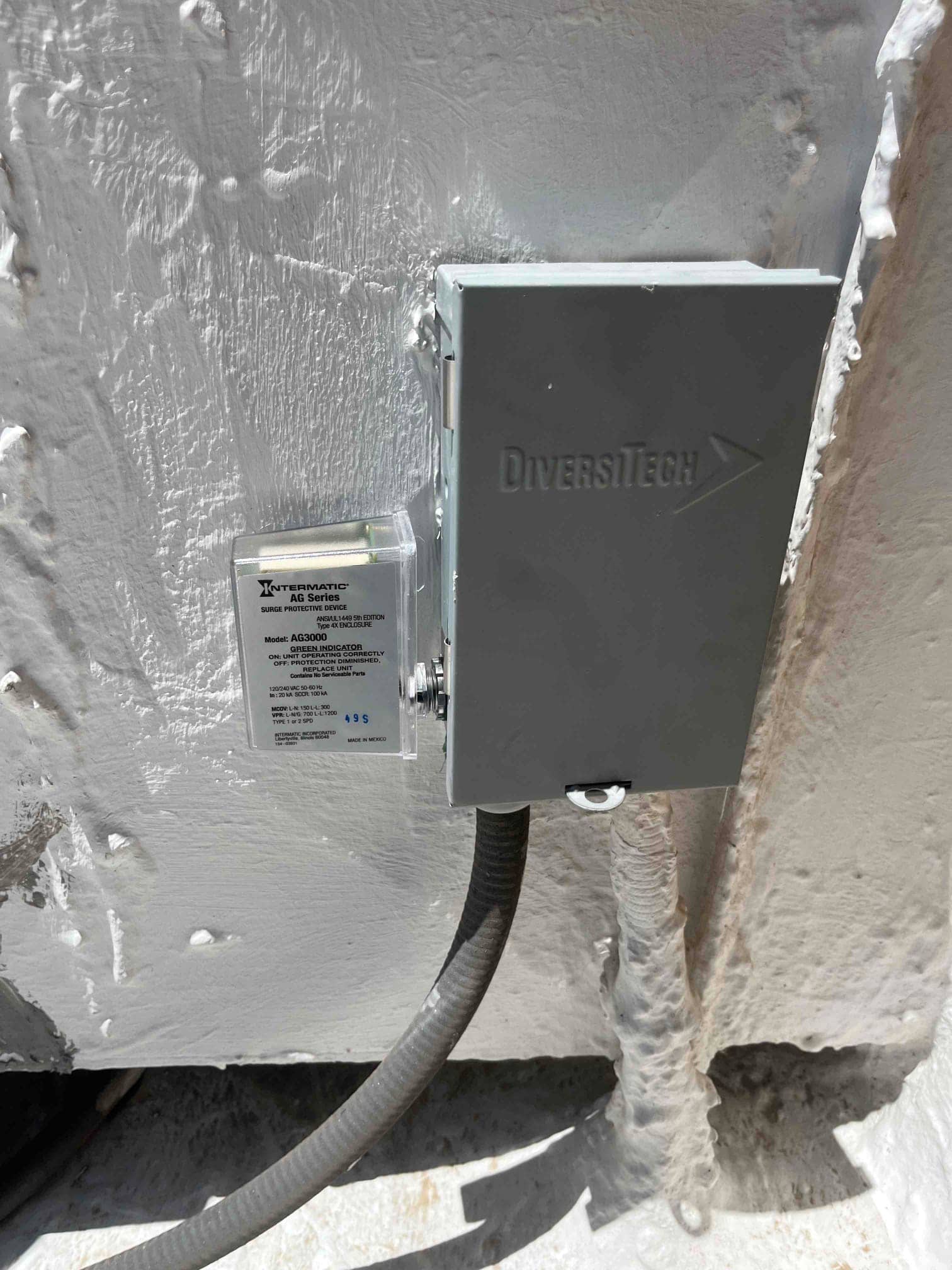 Surge protector installed next to the outdoor disconnect, with flexible conduit entering the weatherproof enclosure.