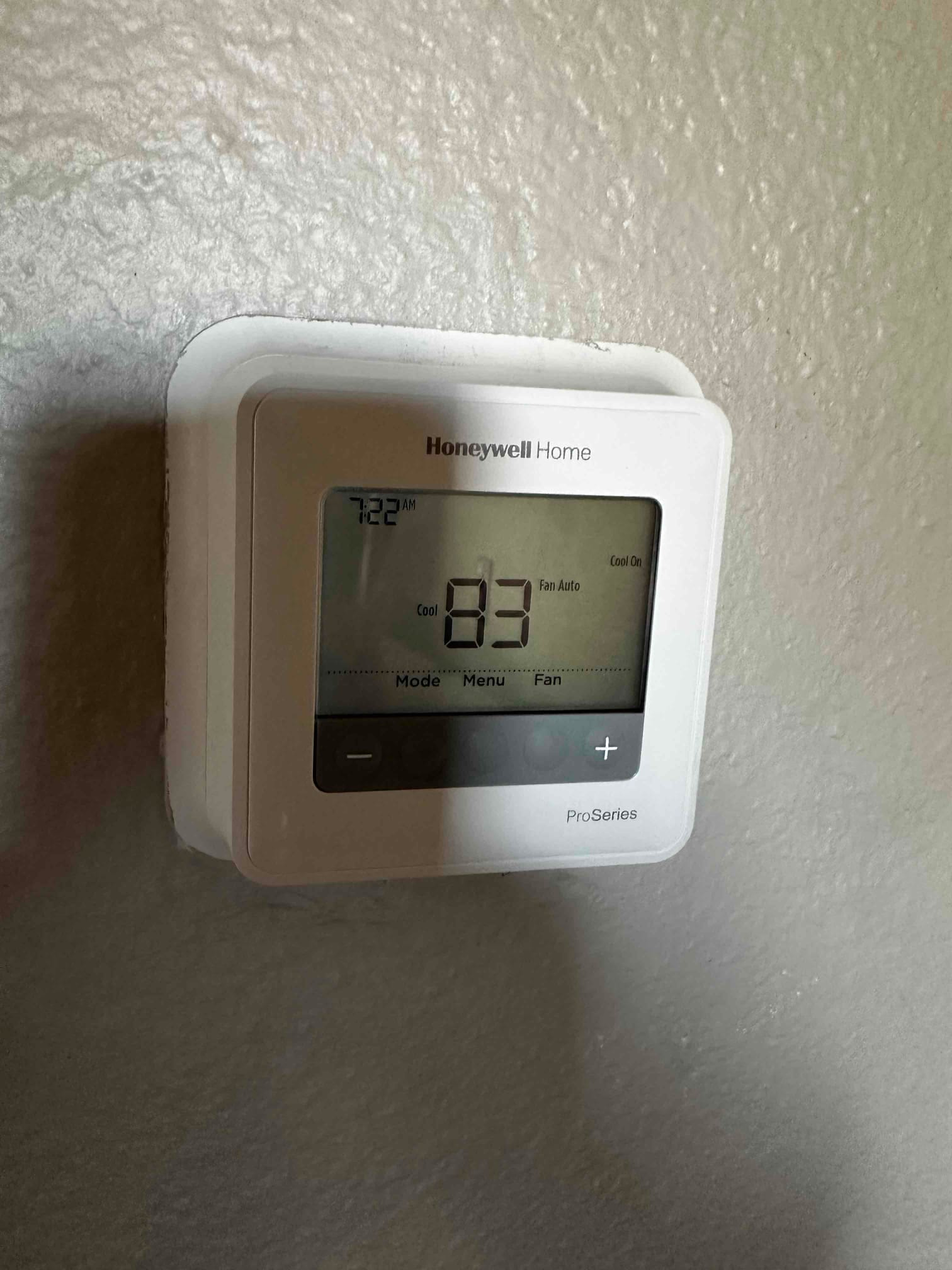 Wall-mounted digital thermostat installed and powered, displaying cooling mode with fan set to auto.
