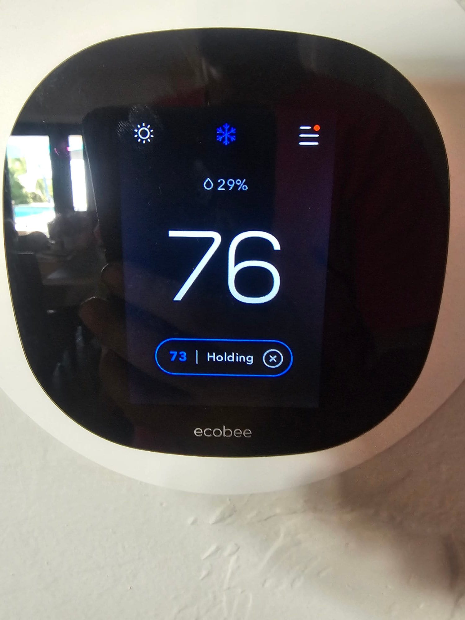 Wall-mounted smart thermostat shows cooling mode active with indoor temperature at 76 degrees and setpoint holding at 73.